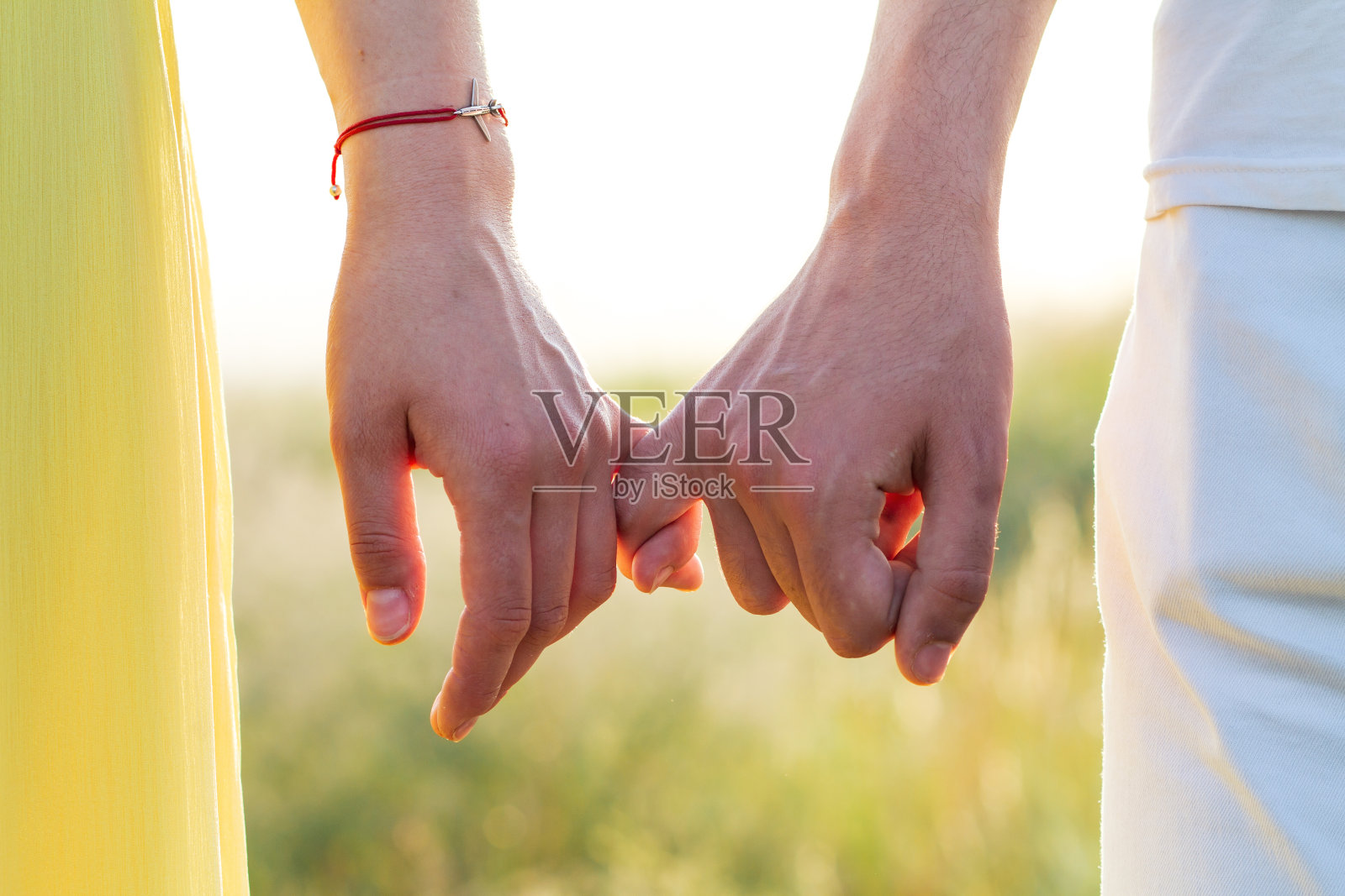 一个男孩和一个女孩在大自然中牵着小孩子的手。夏田和相爱的两个人相爱,浪漫而又散步。照片摄影图片