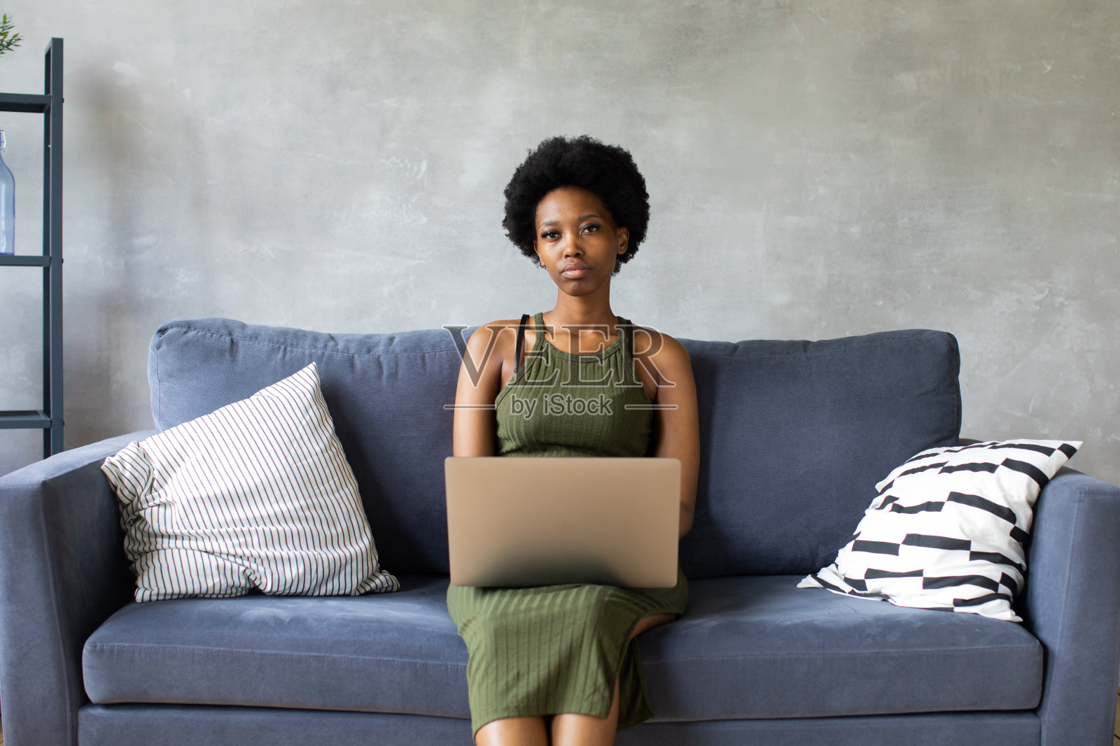 快乐的非洲裔美国年轻女子坐在舒适的沙发上放松,在笔记本电脑上工作。很高兴搬到新公寓照片摄影图片