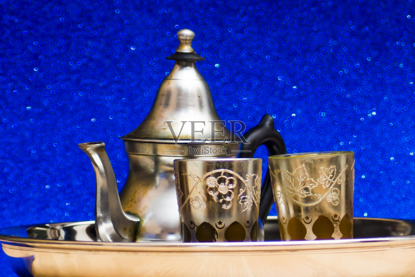 一组茶壶和东方茶在托盘上的蓝色背景闪烁照片摄影图片