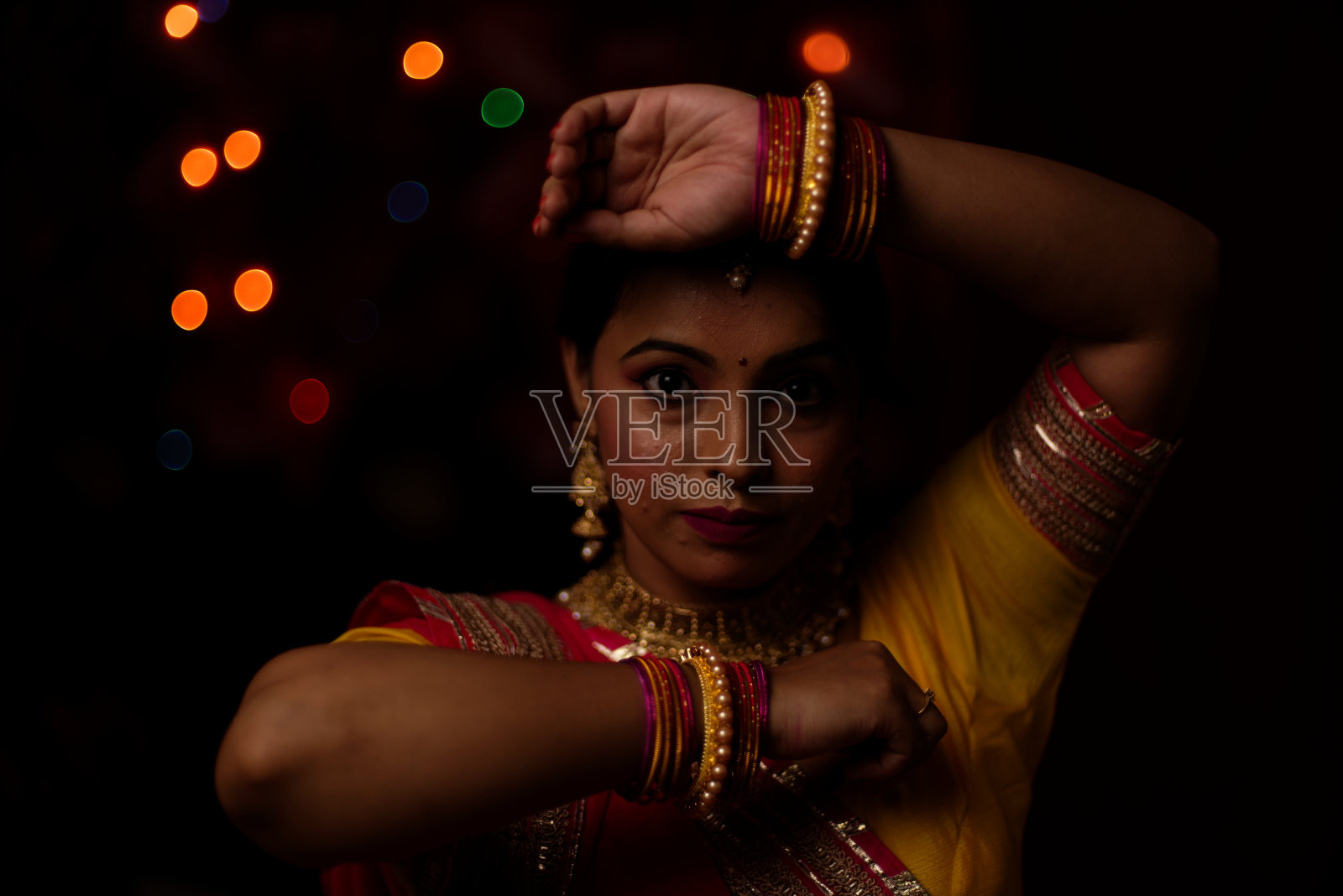 在排灯节的晚上,一个印度孟加拉美丽的黑发女人在五颜六色的光bokeh背景创造的小链灯的肖像。照片摄影图片