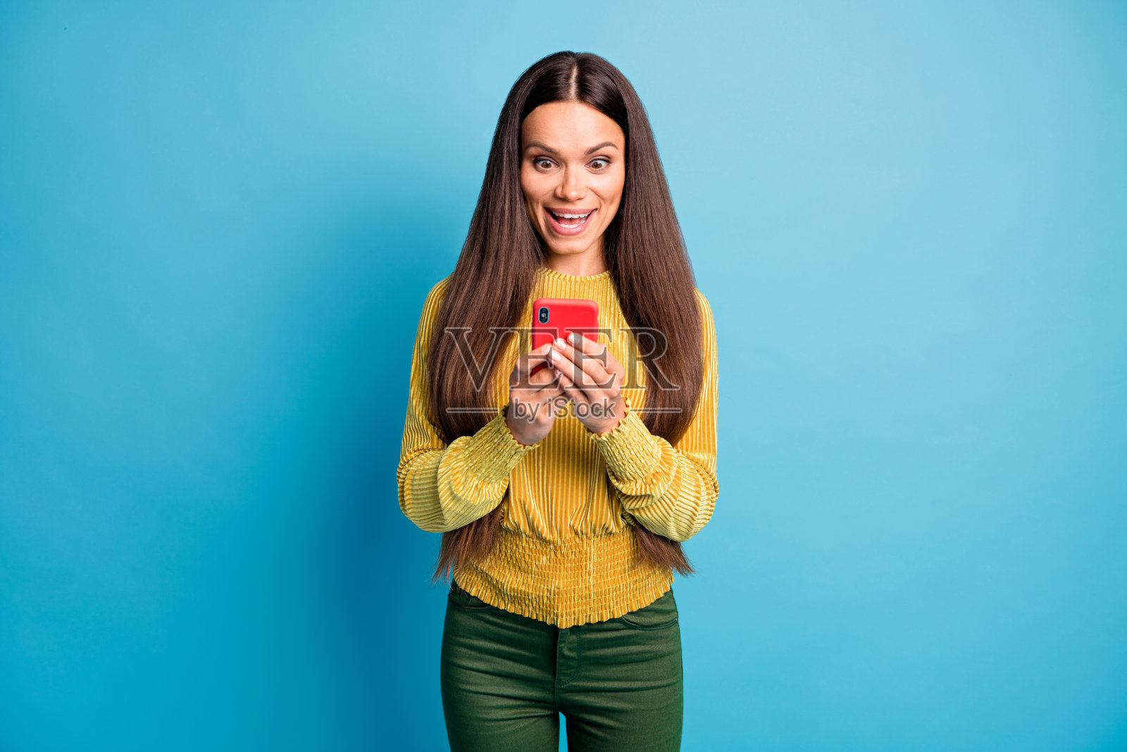 照片肖像的震惊女孩拿着红色手机在两个手孤立在柔和的蓝色背景照片摄影图片