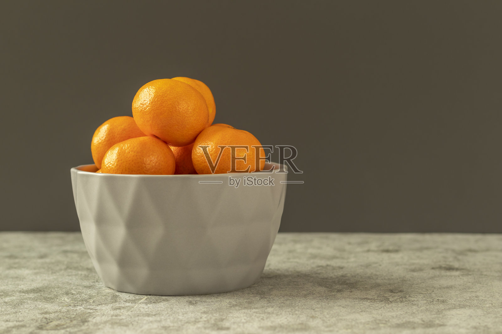 新鲜的有机柑橘,橘子,水果在灰色的碗在灰色的石头背景。选择性聚焦,侧视图和复制空间照片摄影图片