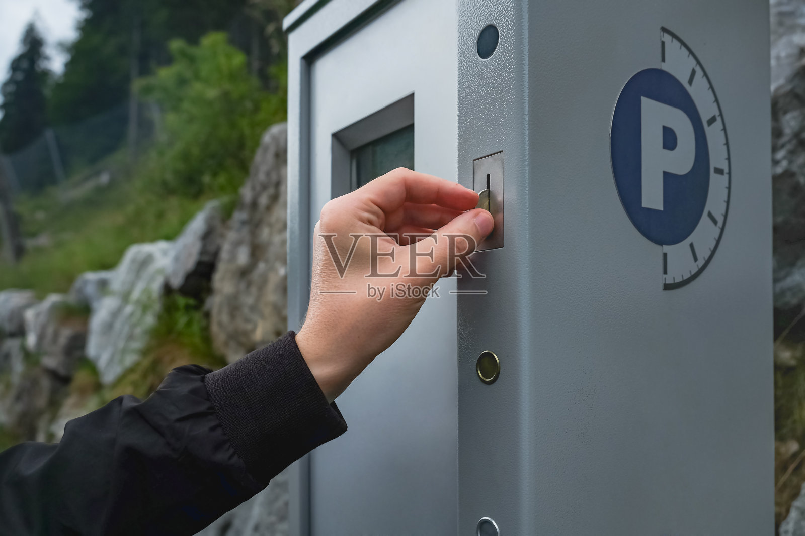 一名白人男子往停车收费表里投了一枚硬币来付他的停车罚单照片摄影图片