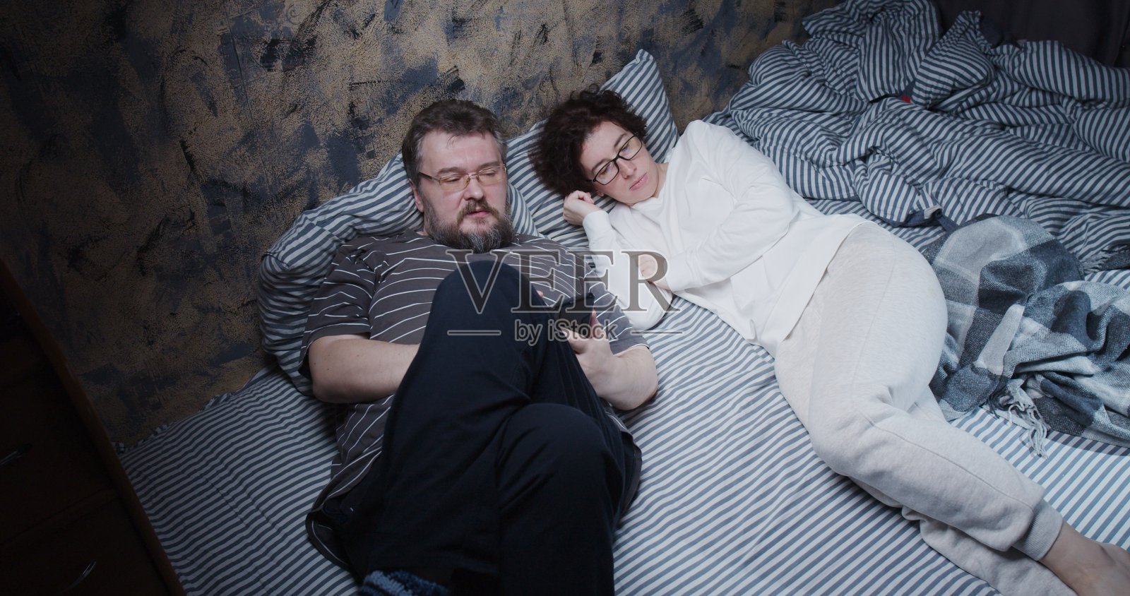 成熟的夫妻在床上看电视照片摄影图片