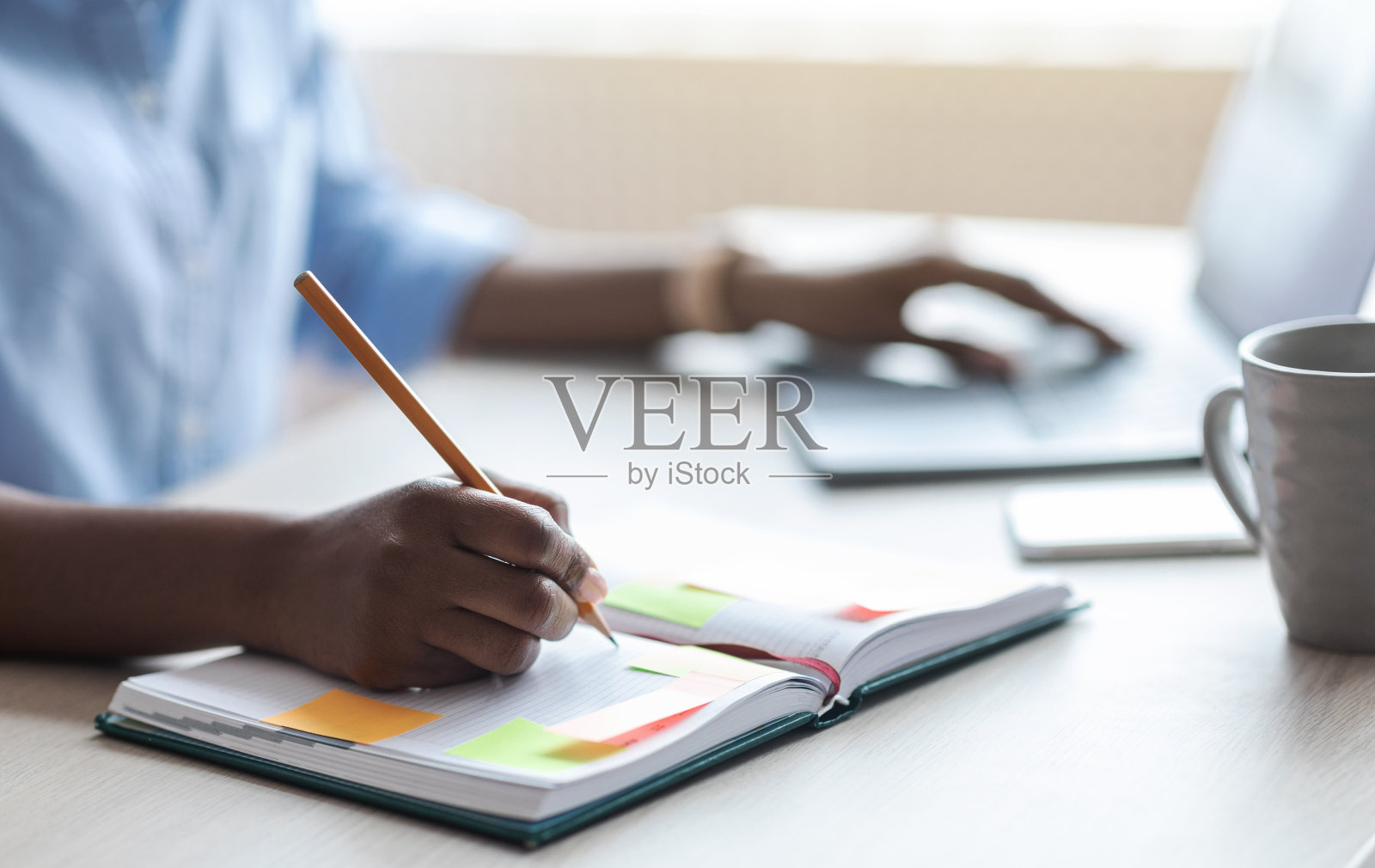 一个不知名的女人在记事本上写东西,在办公室里做笔记照片摄影图片