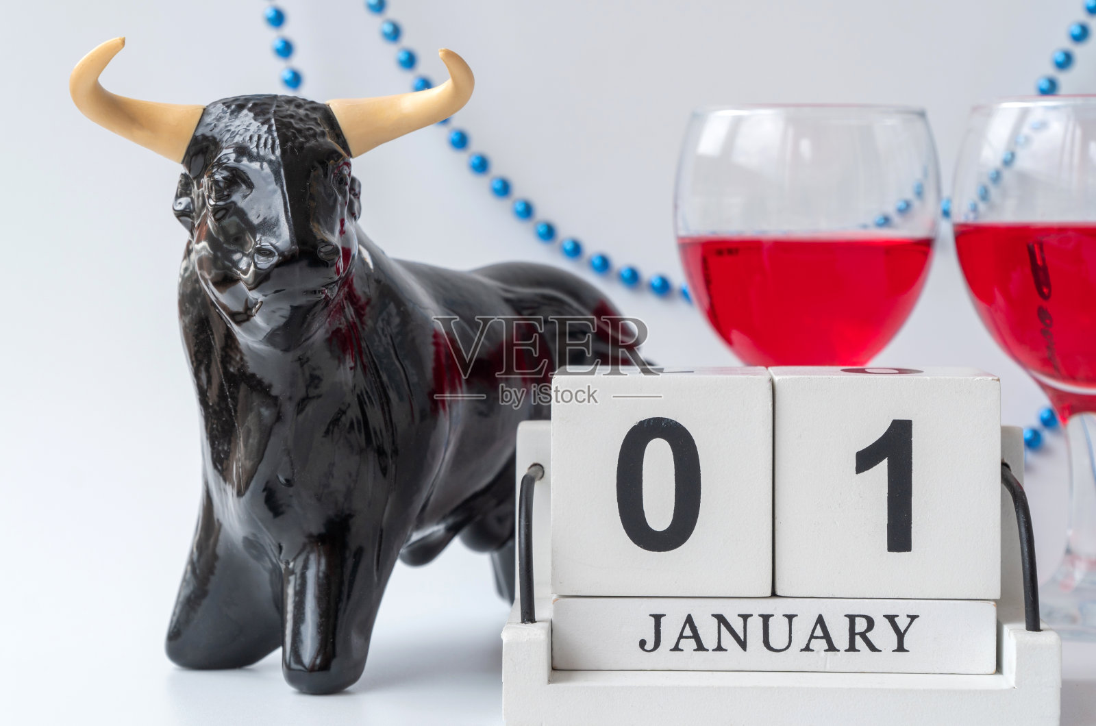 牛,用珠子装饰。背景中的酒杯。有选择性的重点。手工木方与日期,月和日。1月1日。公牛作为新年和2021年圣诞节的象征照片摄影图片