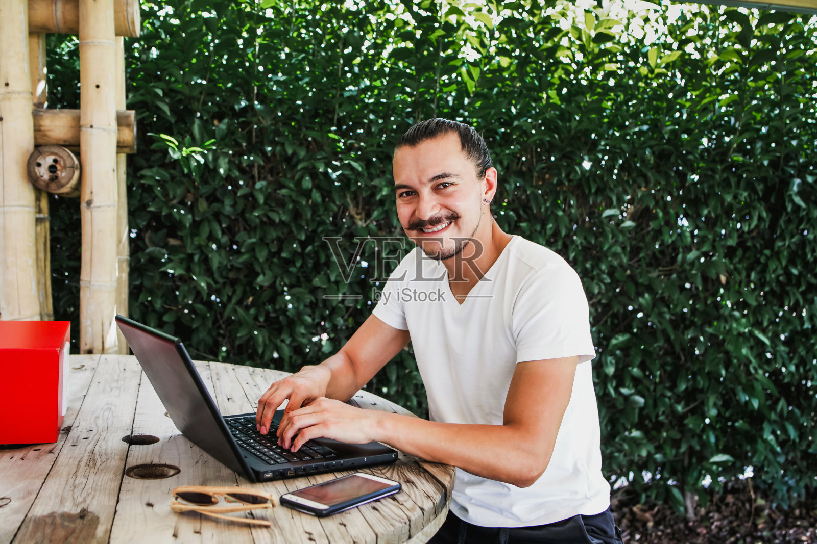 在墨西哥城的家庭工作中,一个拉丁人在一个美丽的露台上使用智能手机和电脑工作照片摄影图片