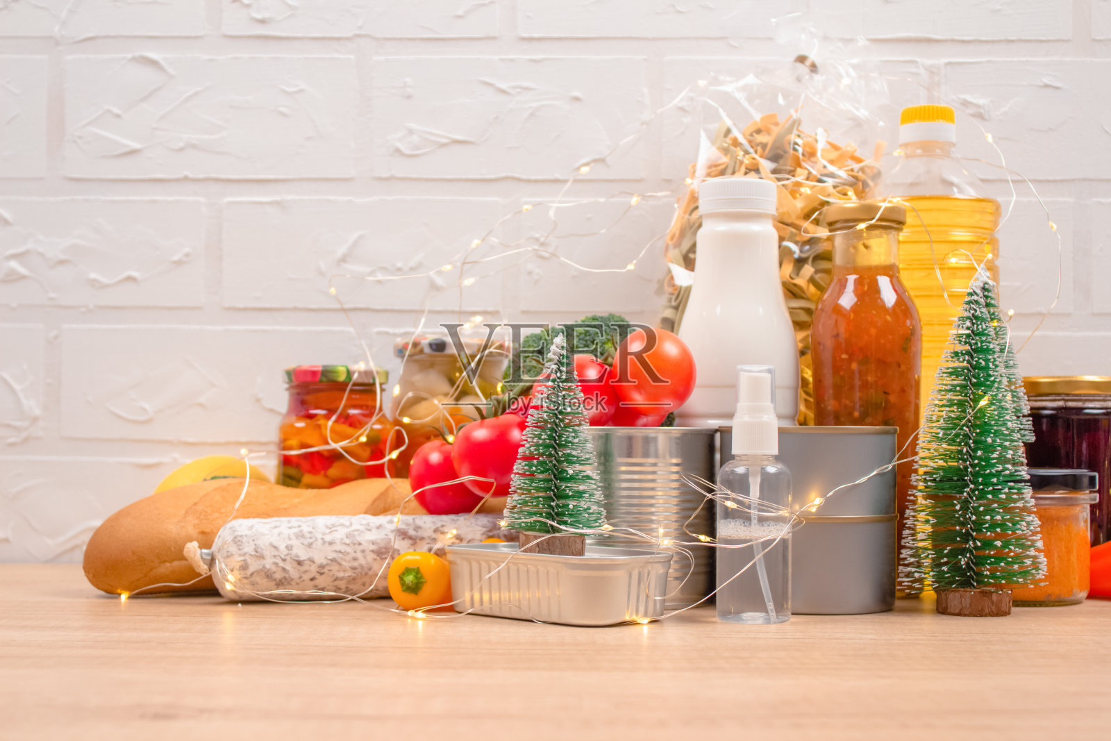圣诞捐赠-食物捐赠的光背景与copyspace -意大利面,新鲜蔬菜,罐头食品,法棍,食用油与圣诞装饰。食物银行。有选择性的重点照片摄影图片