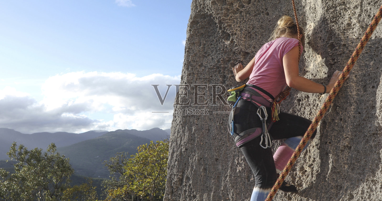 年轻女子攀登陡峭的岩壁照片摄影图片