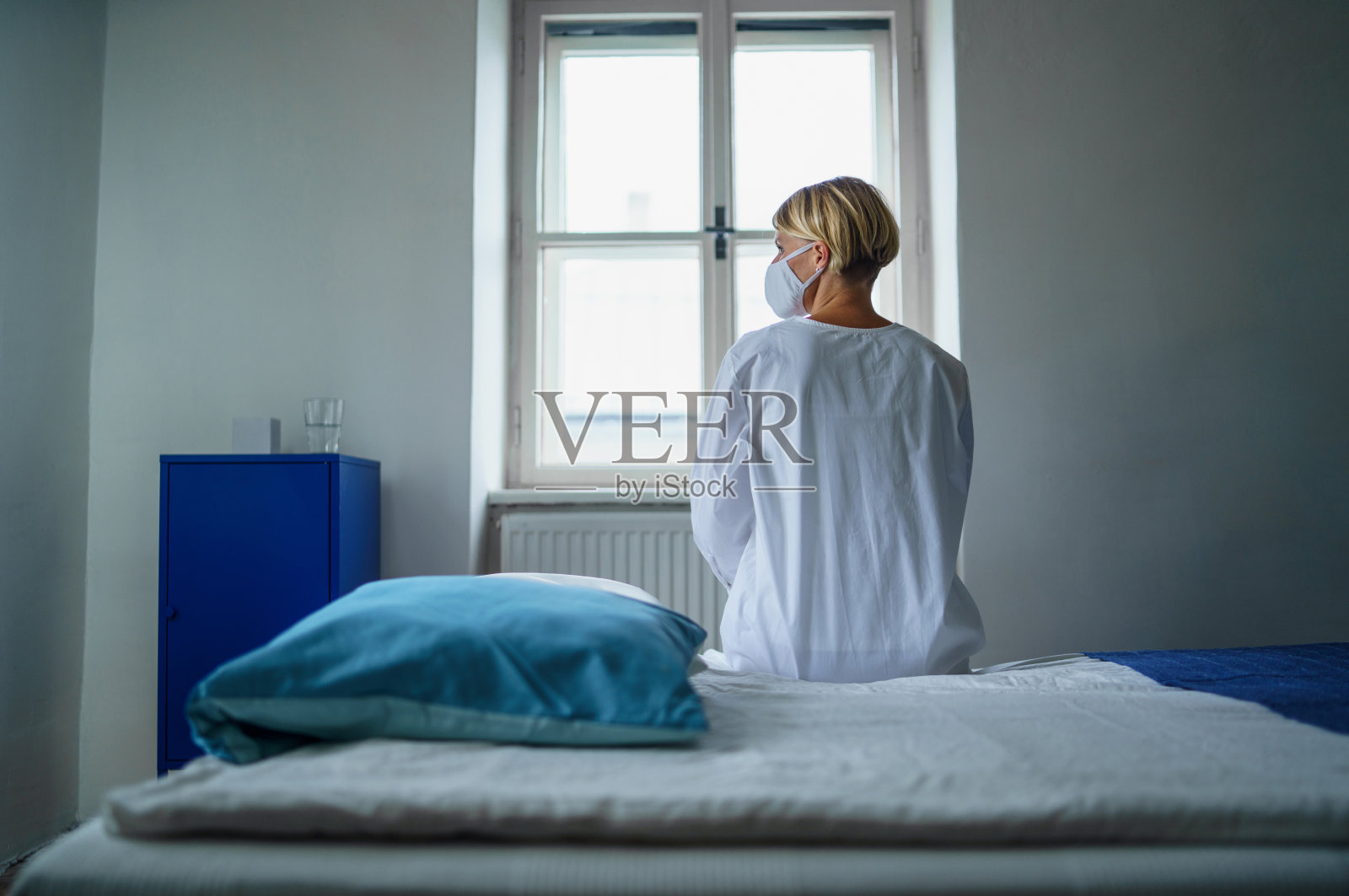 女性患者坐在医院病床上感到压力、心理健康和冠状病毒概念的后视图。照片摄影图片
