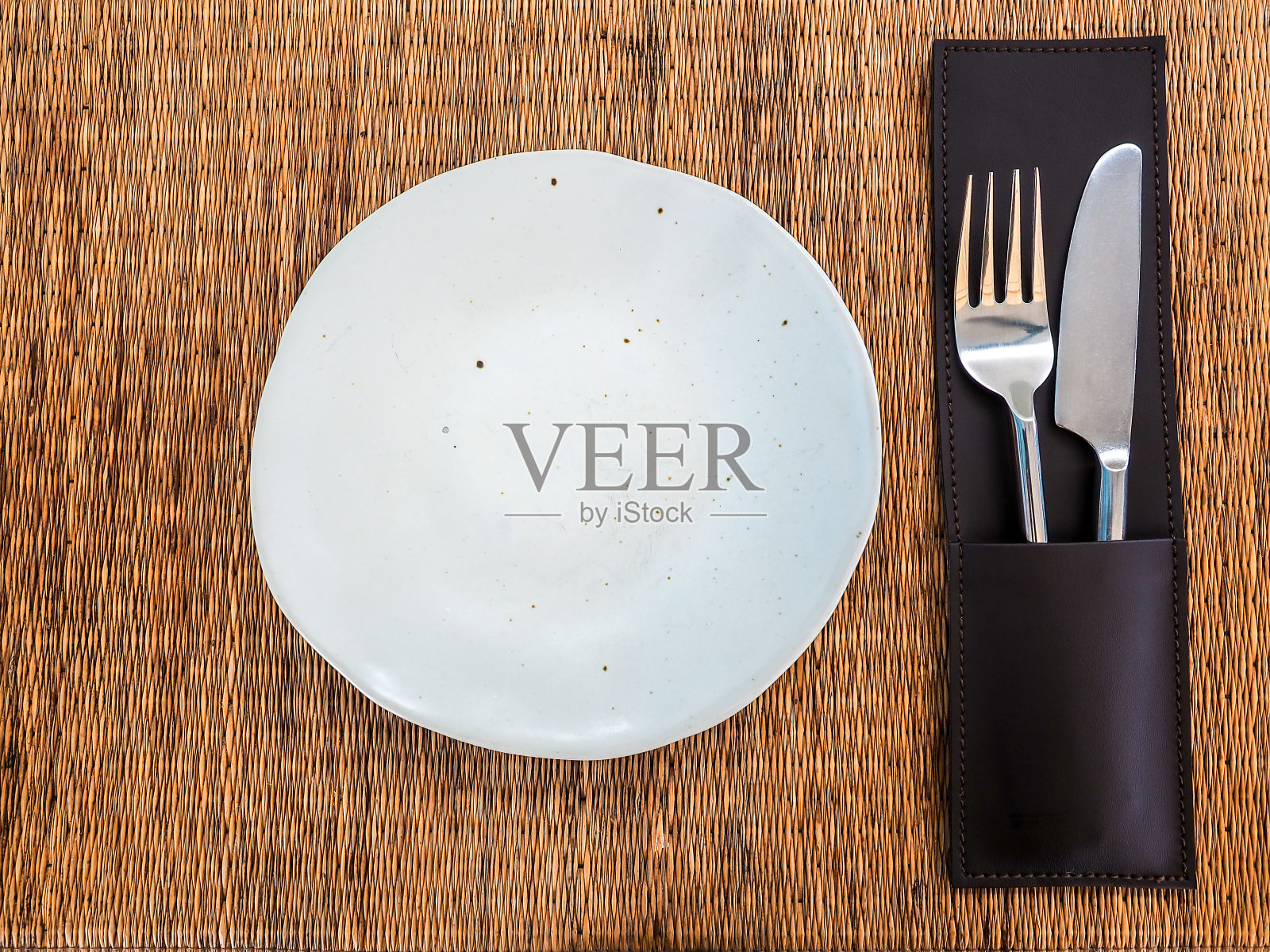 陶瓷板。空白色自由形状的瓷盘,刀叉在皮革盒上垫。照片摄影图片