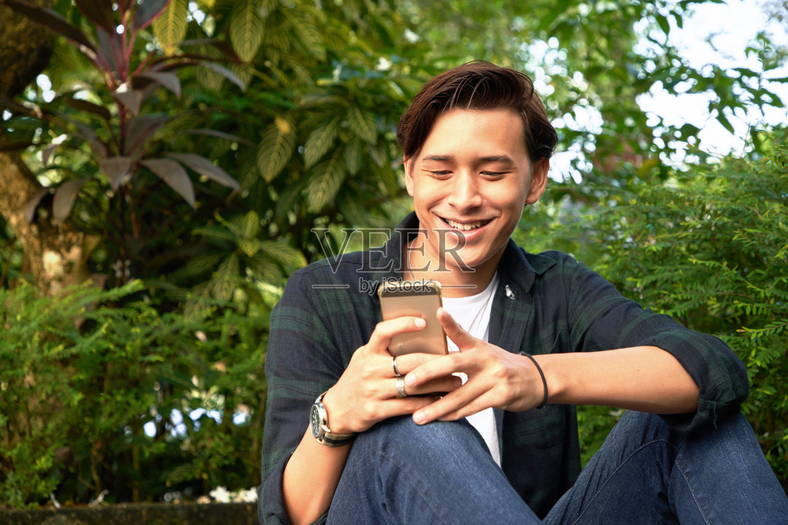 帅哥坐在长凳上享受他的智能手机照片摄影图片