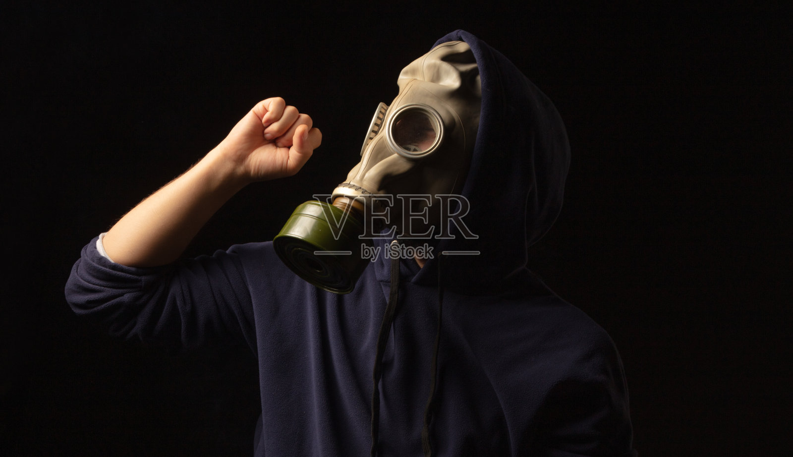 一个戴着防毒面具的男人在空中举着拳头的侧影。照片摄影图片