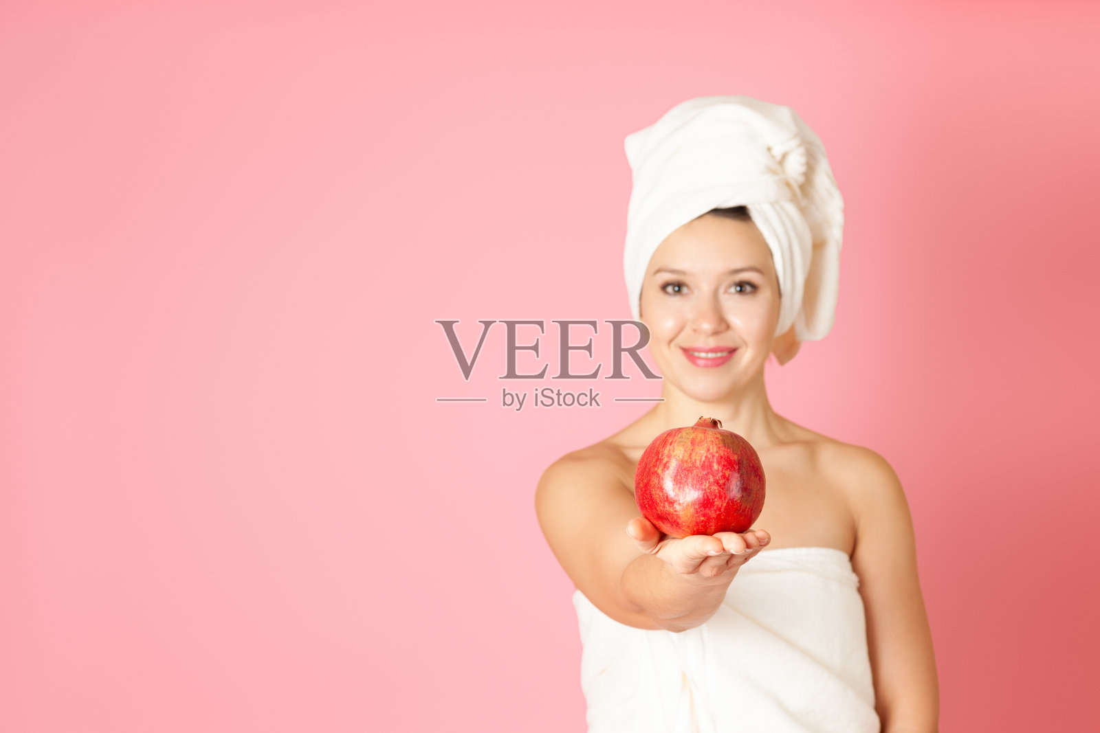 模拟,一个成熟的石榴在一个年轻女子的手掌在粉红色背景散焦照片摄影图片