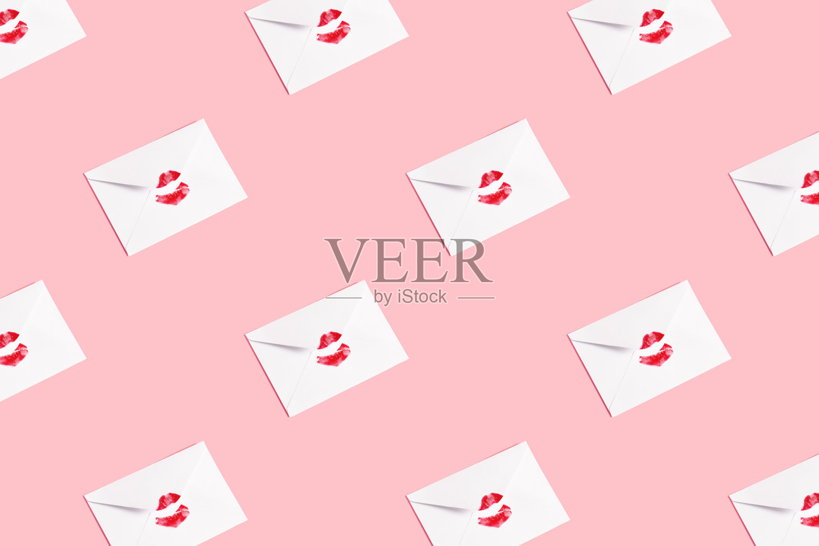 红唇之吻印在白色信封上,粉彩背景。照片摄影图片