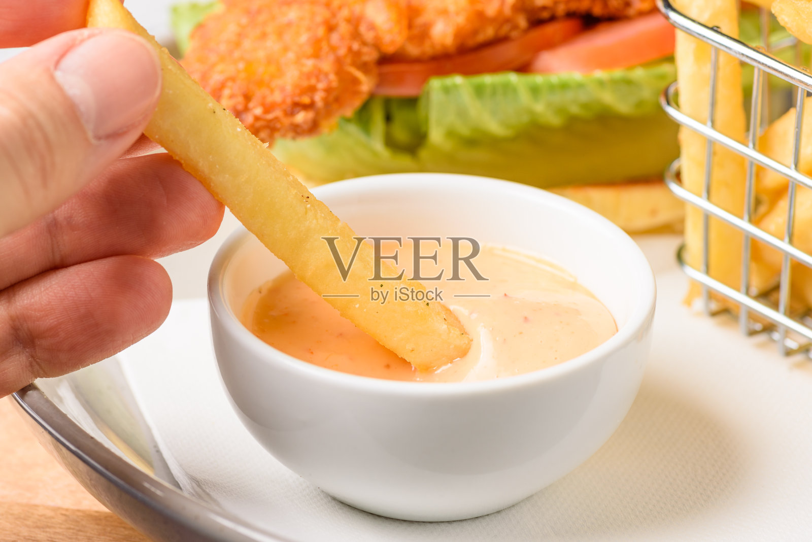 把薯条蘸到一碗酱汁里照片摄影图片