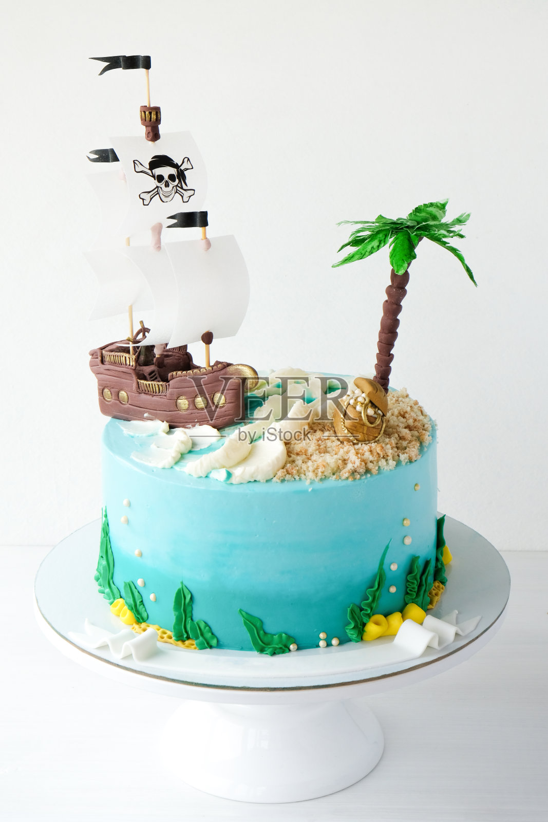 Ake为孩子的生日以海盗为主题,装饰以海浪、船、骷髅、棕榈树、宝箱为白色背景。照片摄影图片