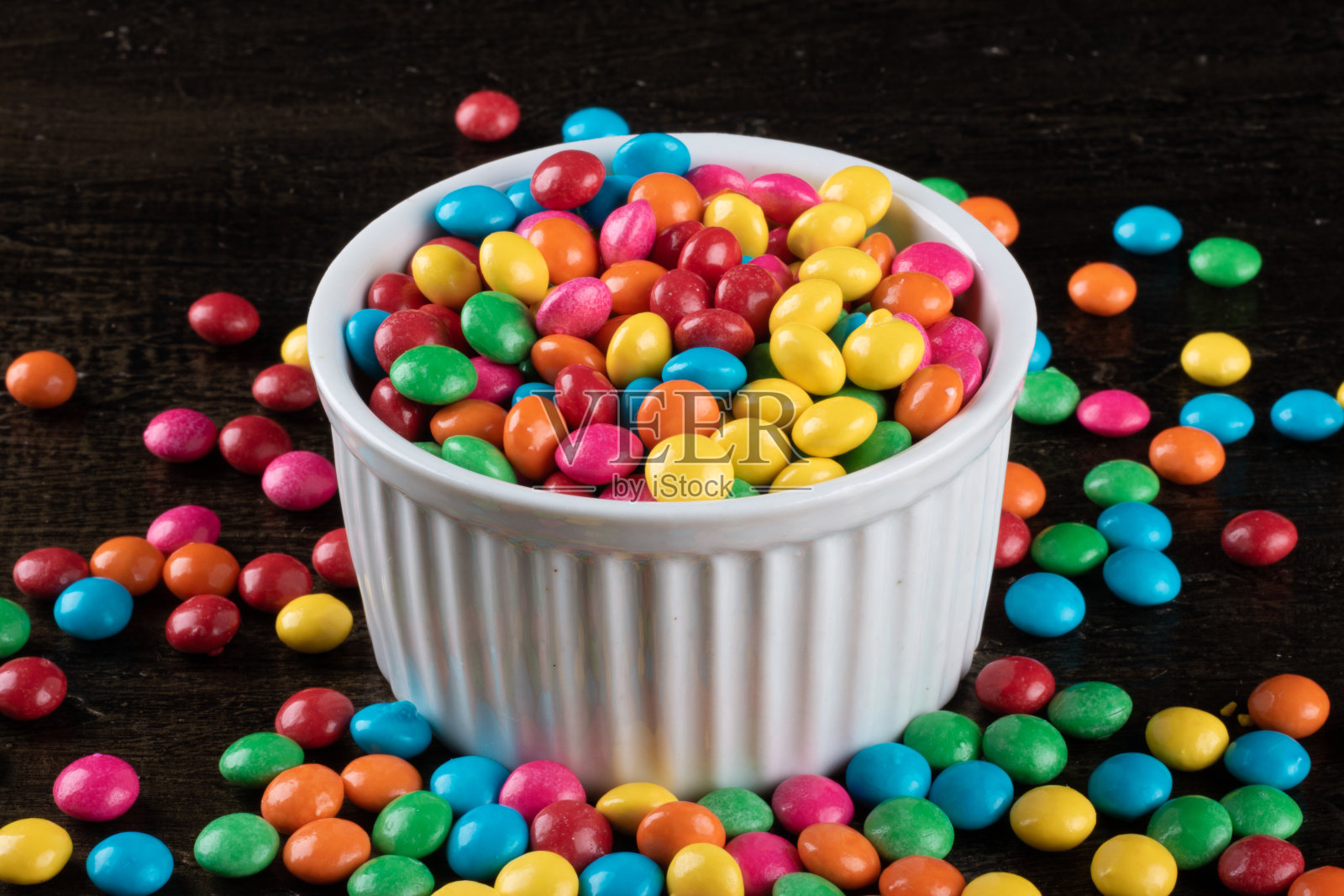 桌上的碗里放着五颜六色的五彩糖果。照片摄影图片