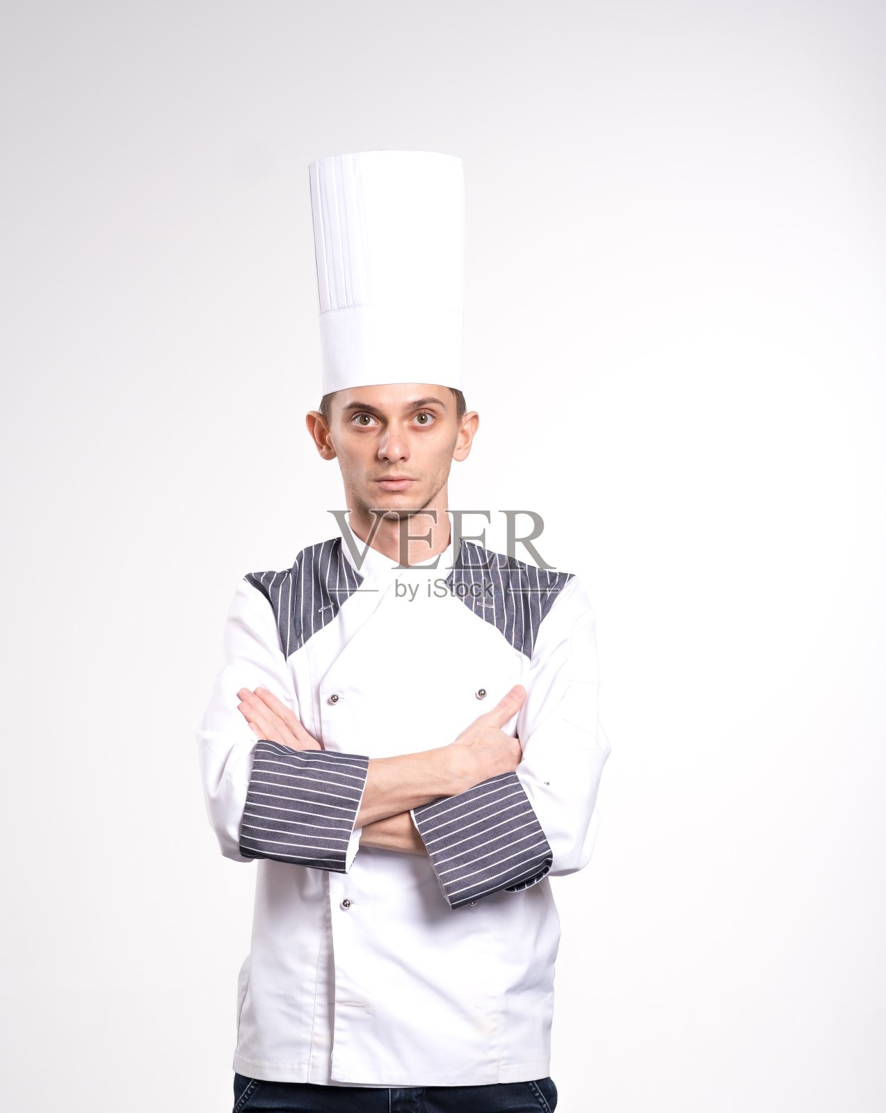正面帅气的厨师厨师在贝雷帽和白色的服装孤立在白色的背景。喜快乐的年轻厨师摆出孤立的白色墙壁背景在制服。照片摄影图片