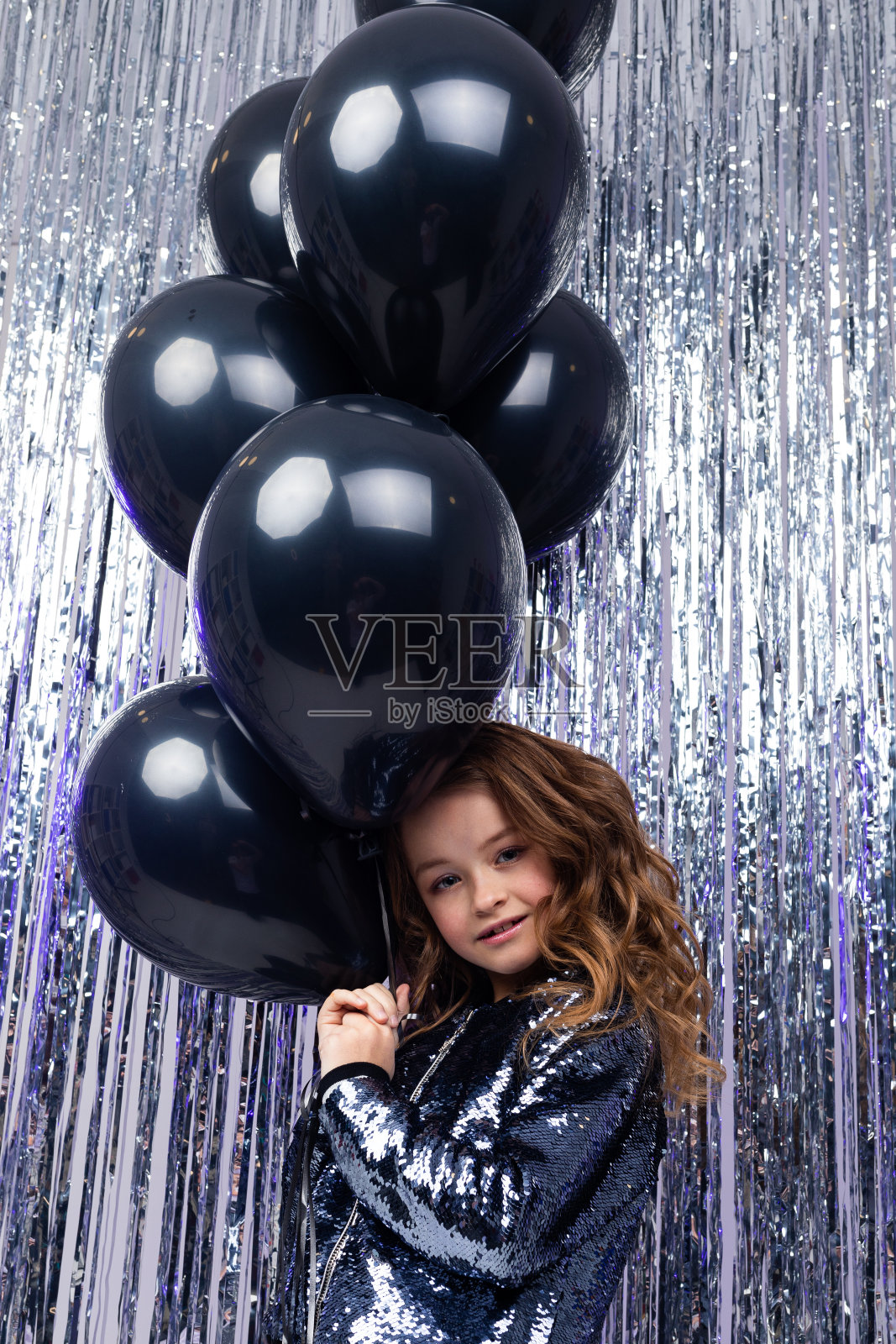 “黑色星期五”。迷人的年轻时尚的白人女孩站在黑色的氦气球在一个闪亮的节日背景照片摄影图片