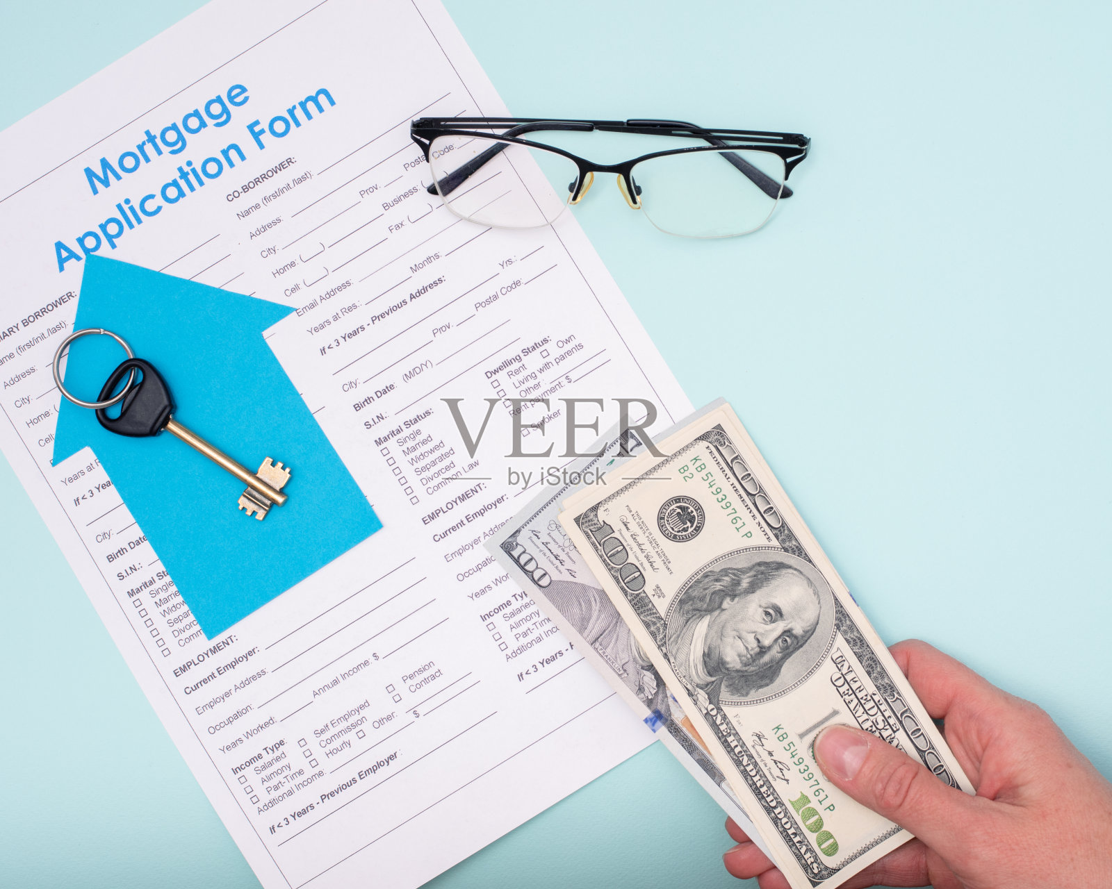 手里拿着钱的美元在抵押申请表上买房子或公寓,钥匙,眼镜照片摄影图片