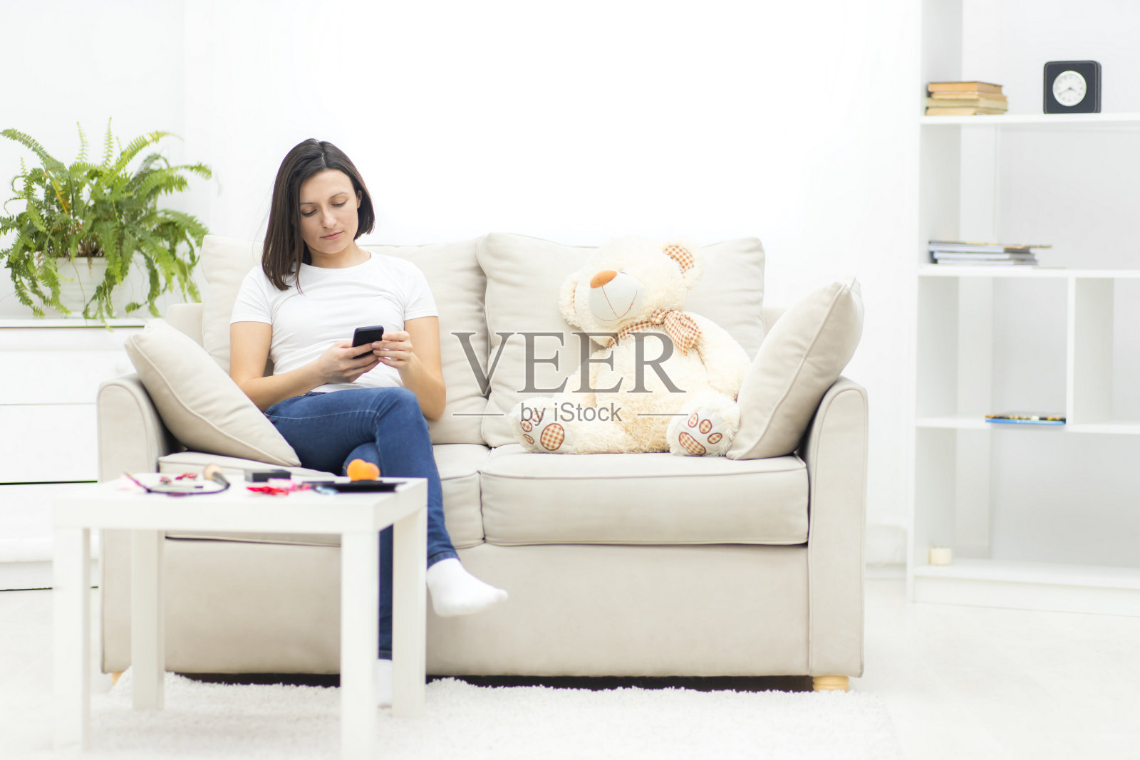 照片中的年轻女子放松在沙发上享受和发短信。照片摄影图片