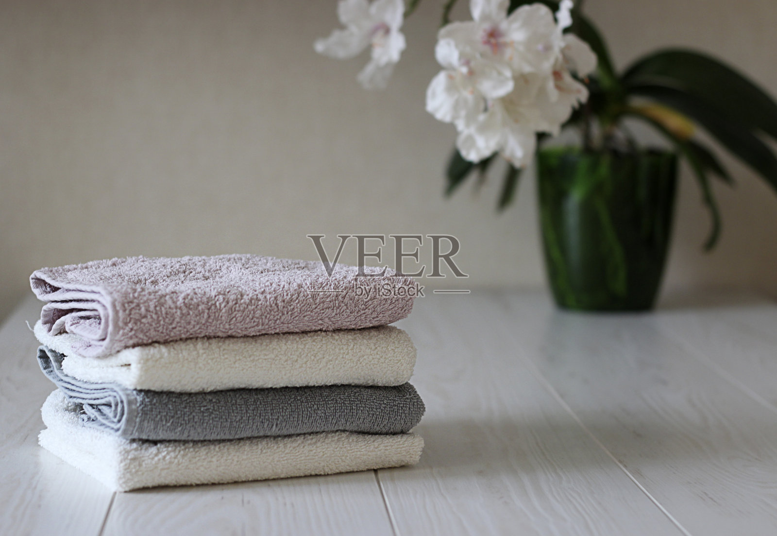 桌上放着四条毛巾,以一朵花为背景照片摄影图片