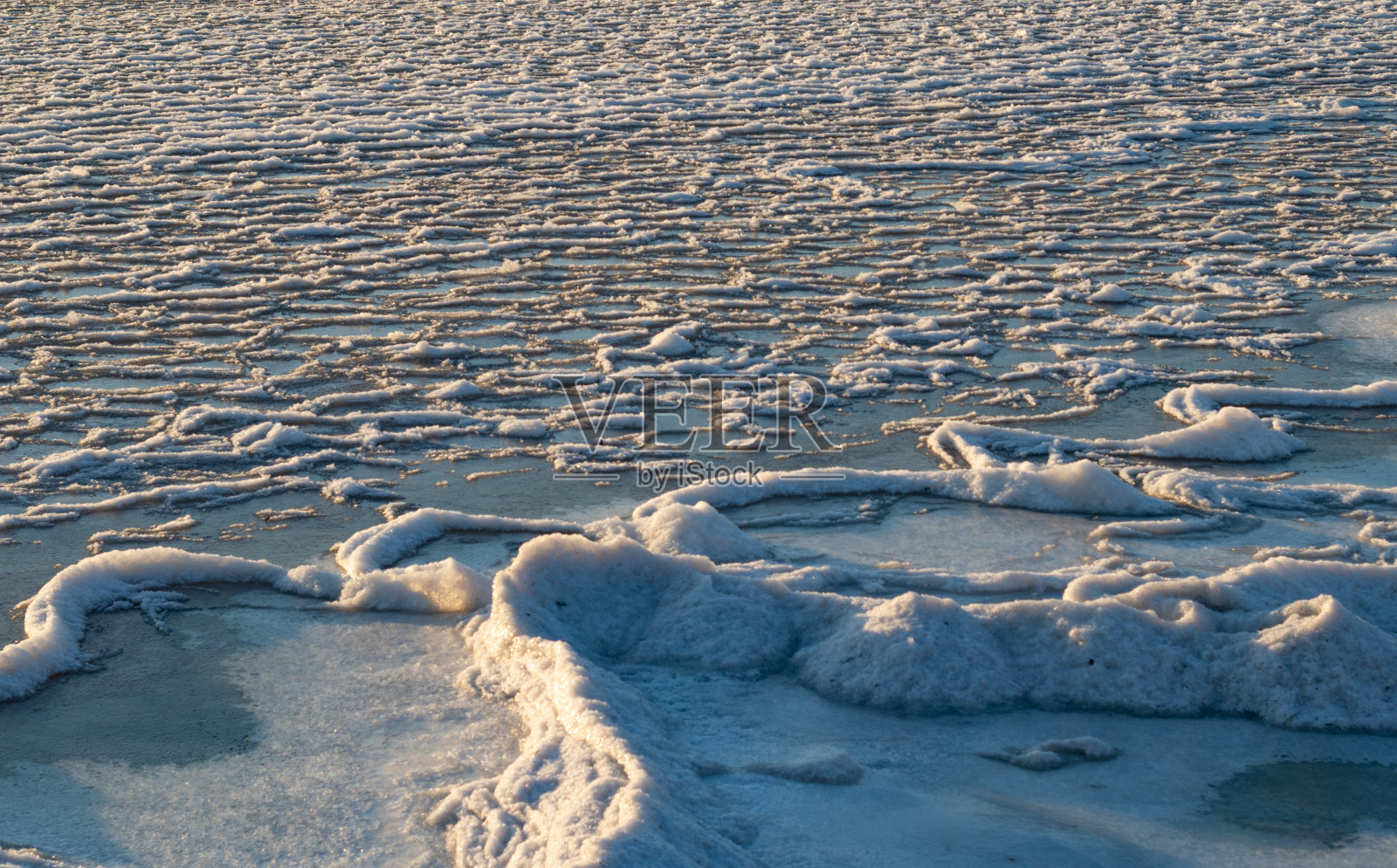 白雪覆盖的海岸。海上冬天的日落。照片摄影图片