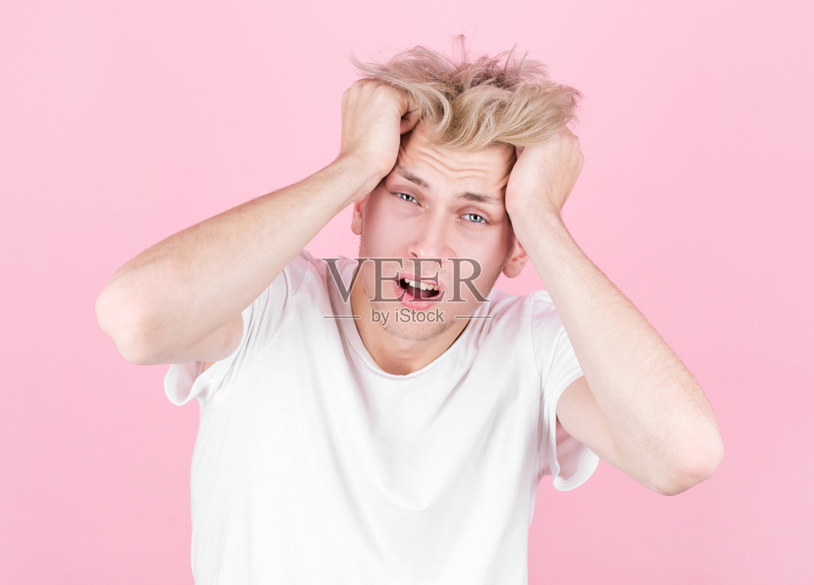 穿着白色t恤的年轻英俊男子在派对后宿醉。宿醉和酗酒的概念。照片摄影图片