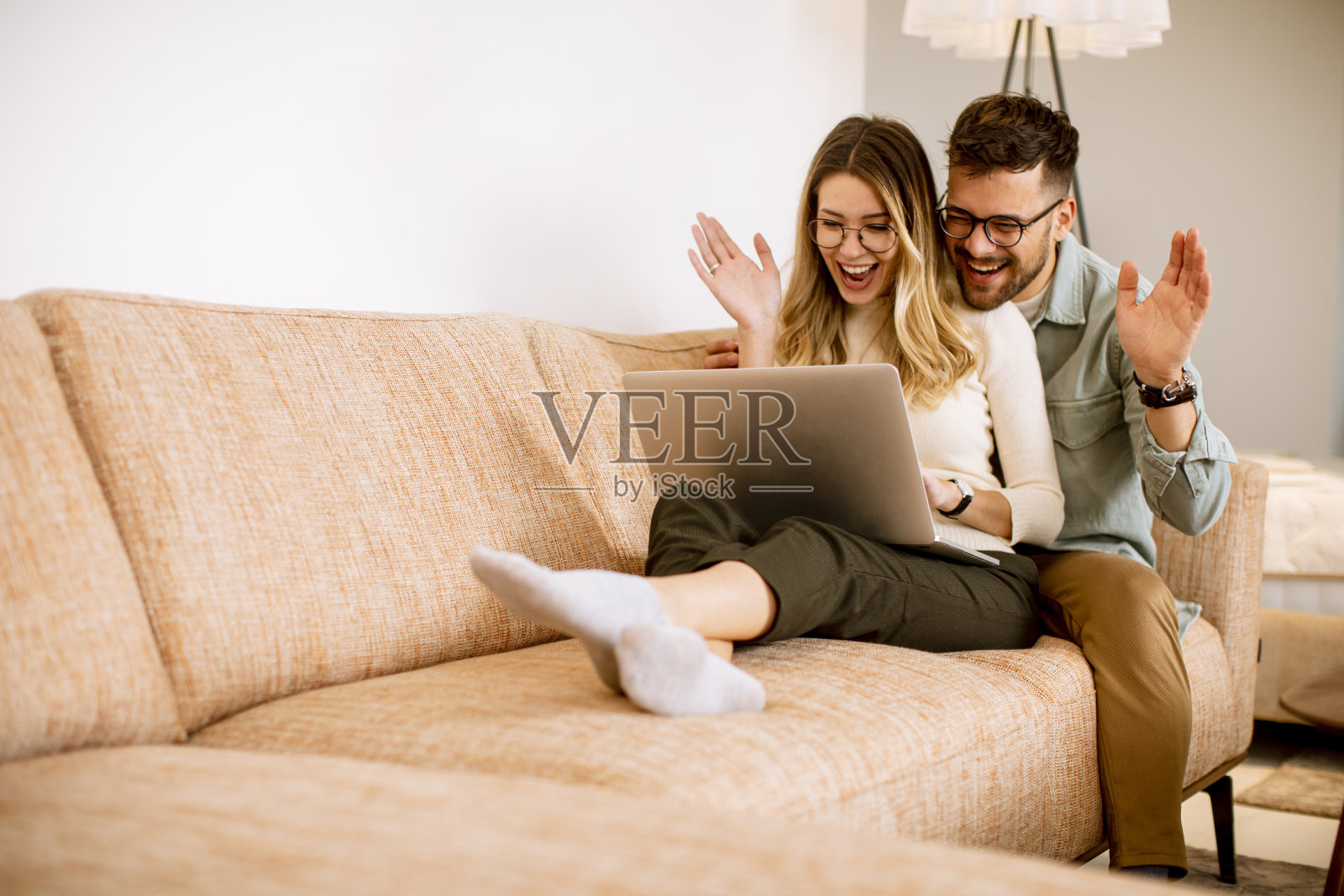 一对年轻夫妇坐在家里的沙发上一起使用笔记本电脑照片摄影图片