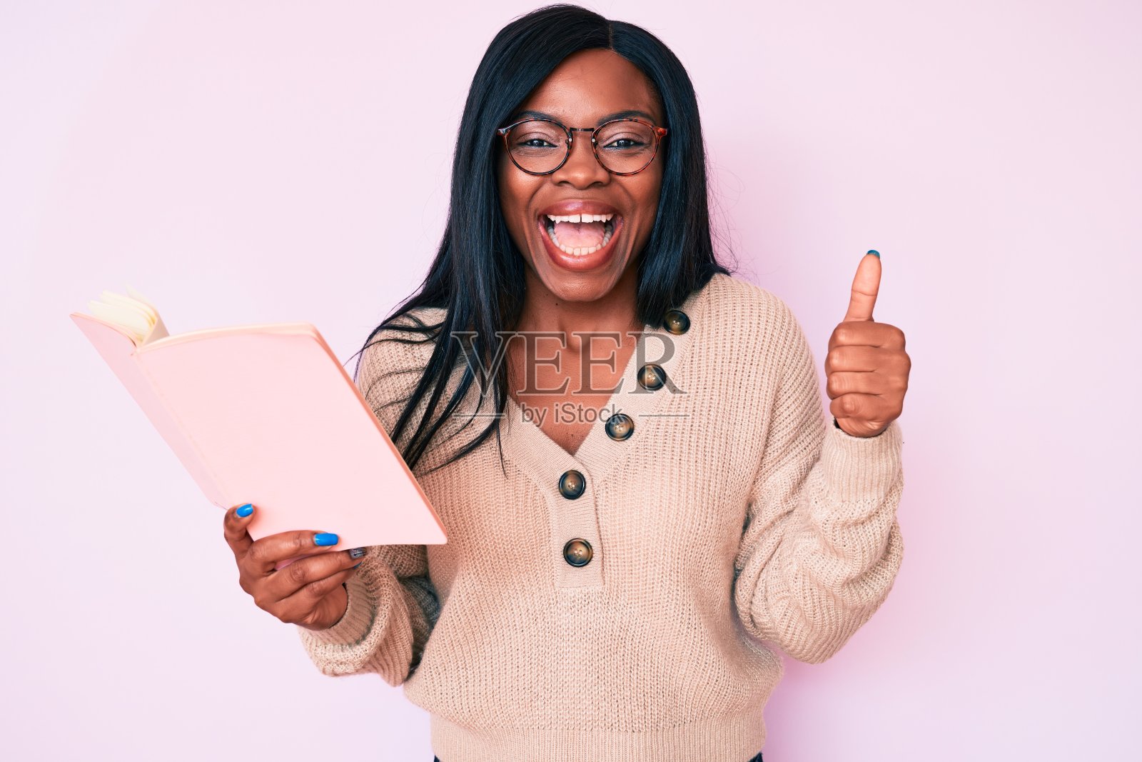 年轻的非洲裔美国妇女戴着眼镜拿着书尖叫着骄傲,庆祝胜利和成功非常兴奋地举起手臂照片摄影图片