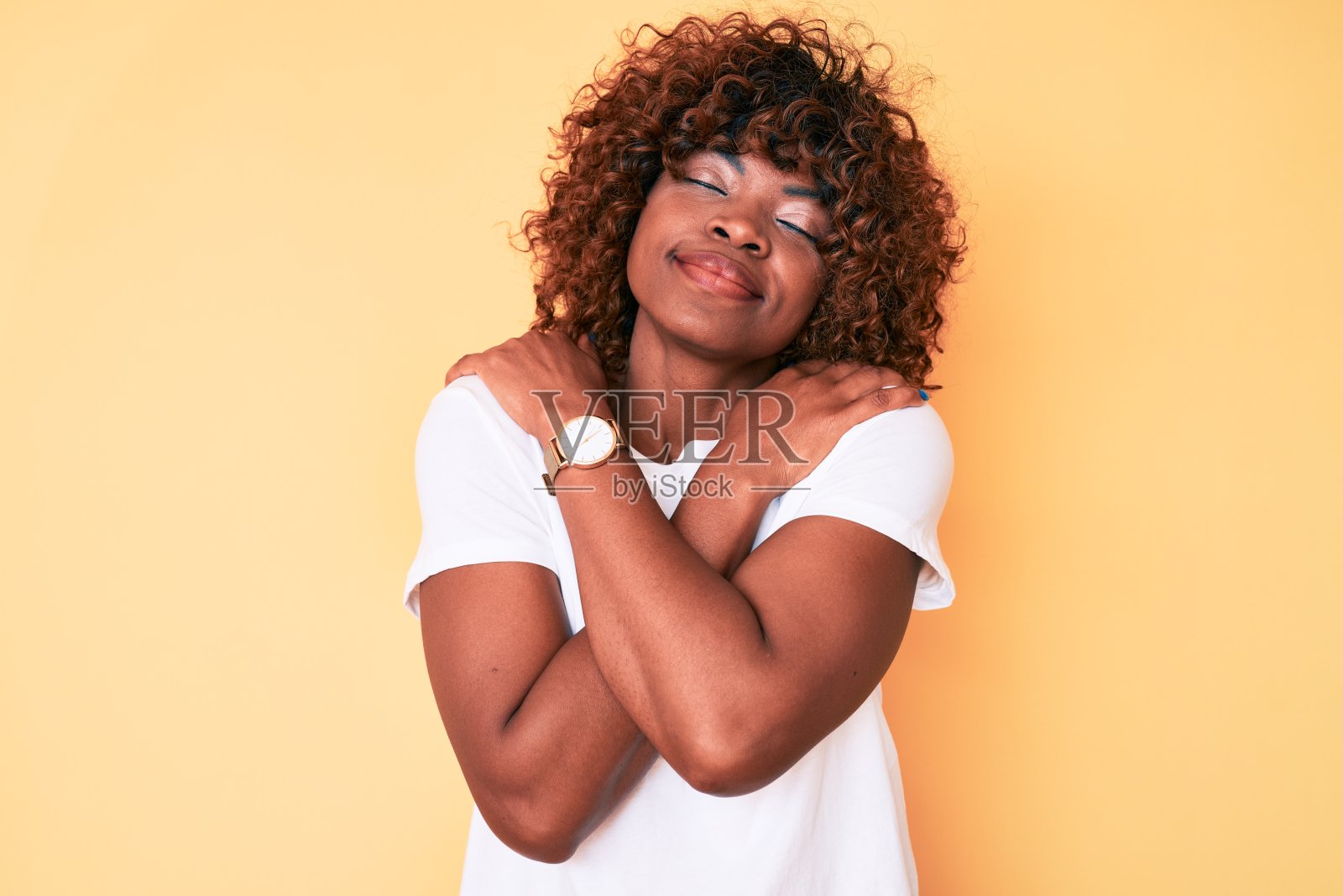 年轻的非洲裔美国妇女穿着休闲的白色t恤拥抱自己快乐和积极,微笑自信。爱自己,关心自己照片摄影图片