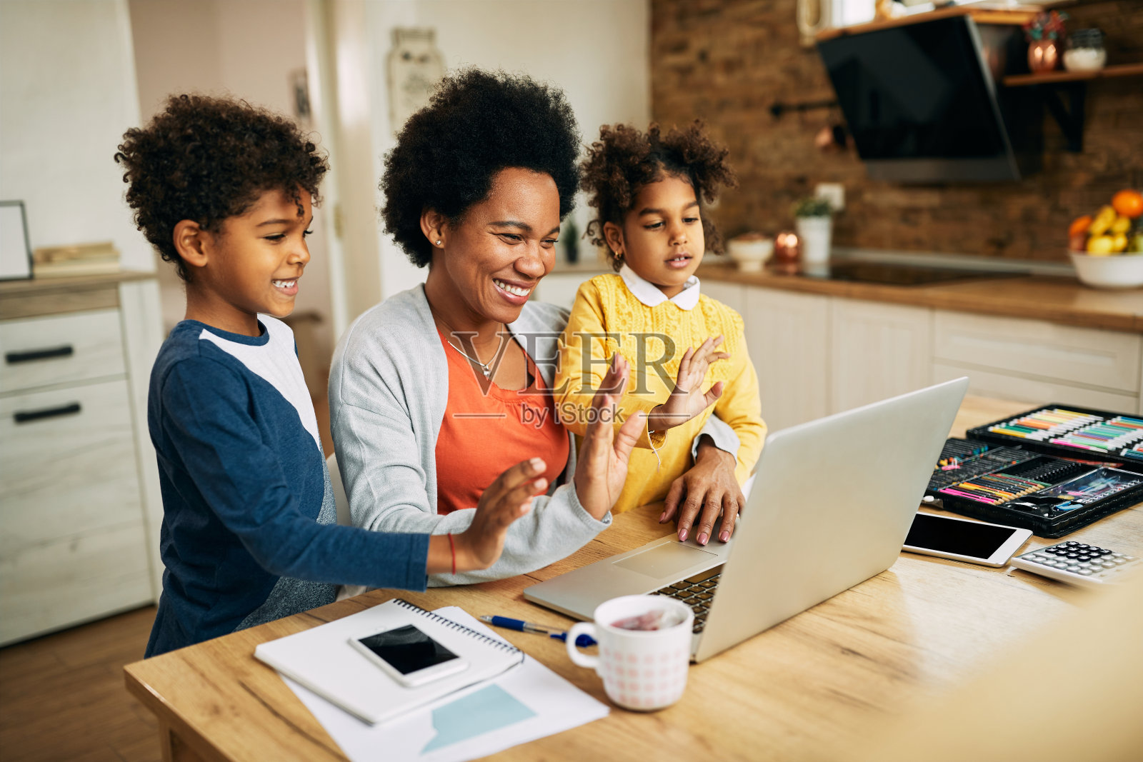 快乐的非裔美国母亲和孩子们在家里用笔记本电脑打视频电话。照片摄影图片