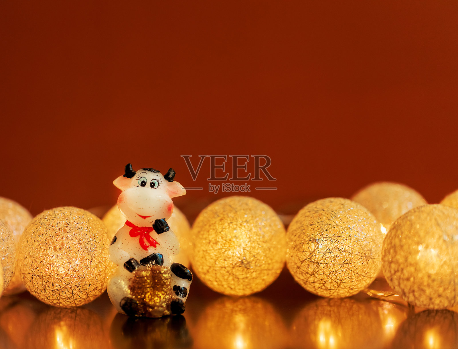 公牛在深色的背景和花环。一头奶牛雕像,棕色背景上有一袋钱。圣诞节,2021年新年,一年的象征。副本的空间。照片摄影图片