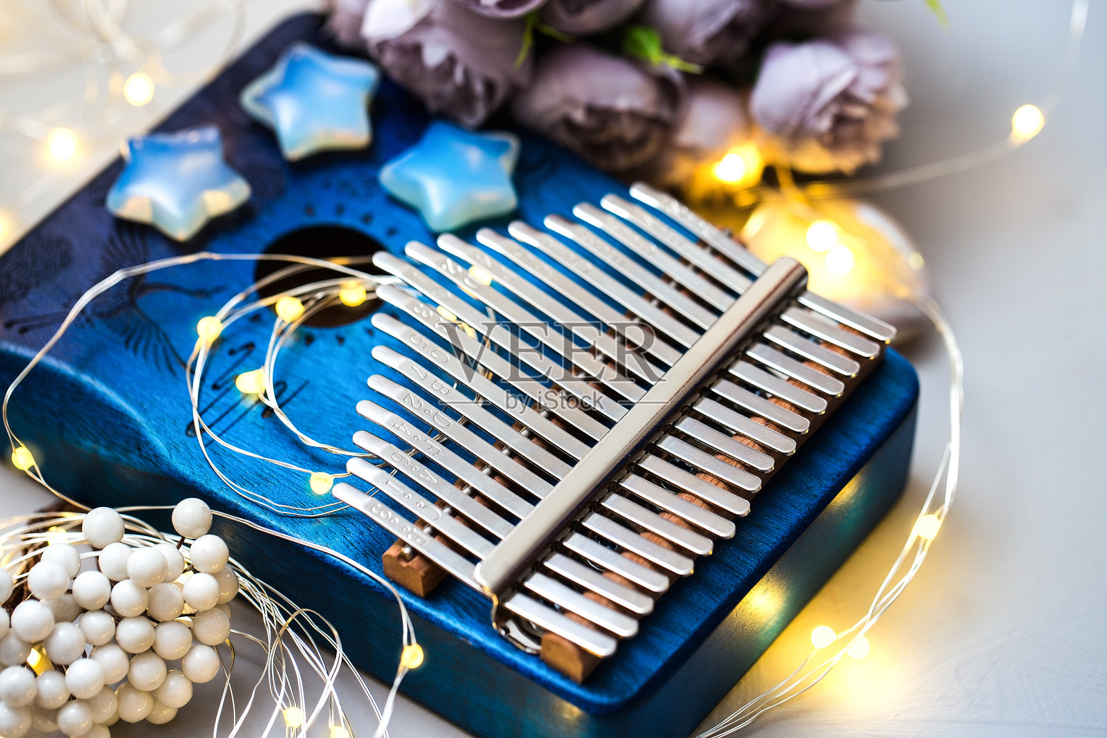 卡里姆巴是一种非洲本土的乐器。音乐盒有漂亮的装饰,灯光,一束花在灰色的背景。创意爱好与音乐艺术疗法照片摄影图片