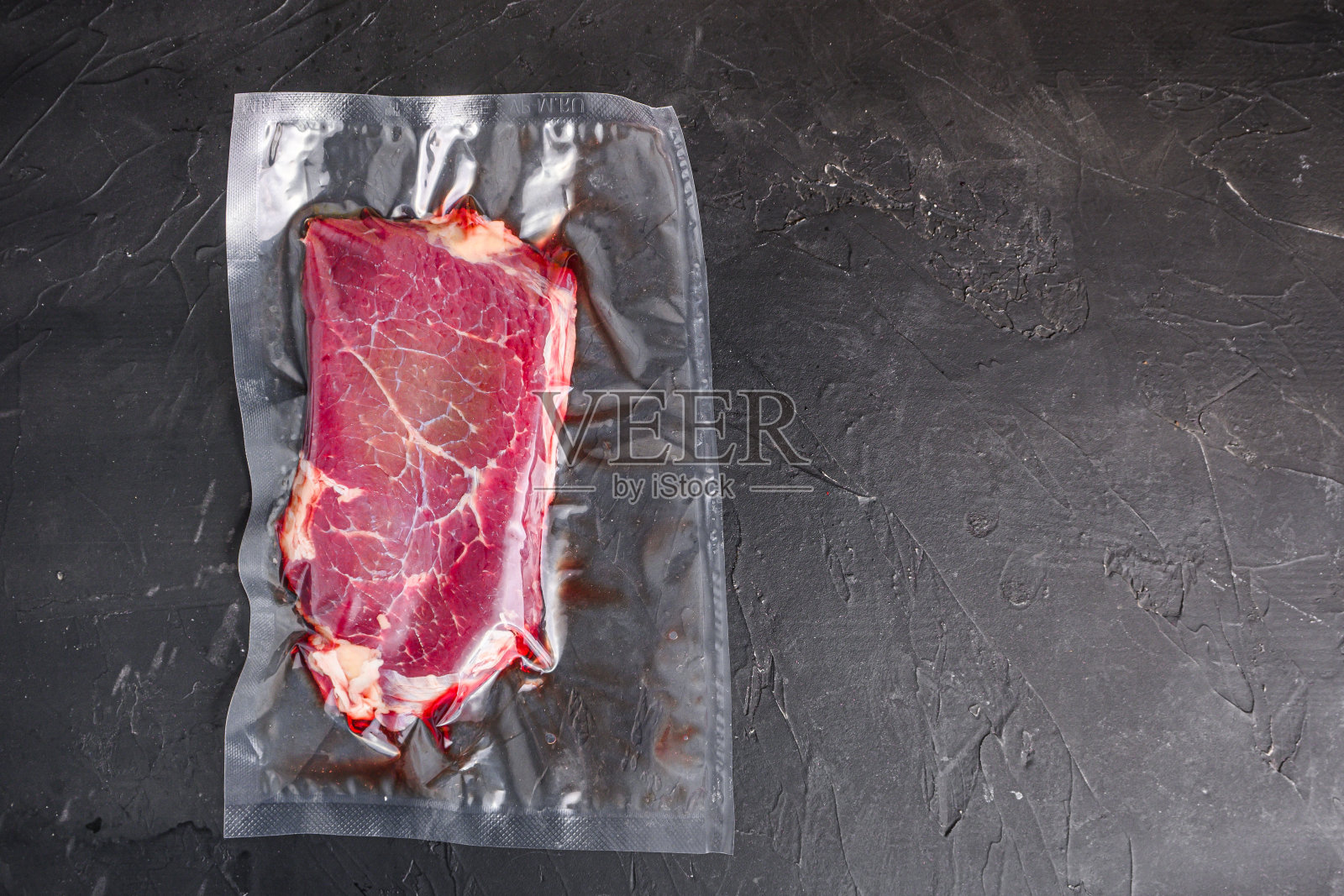 臀牛排真空烹饪在黑色的石头背景,俯视图空间的文本。照片摄影图片