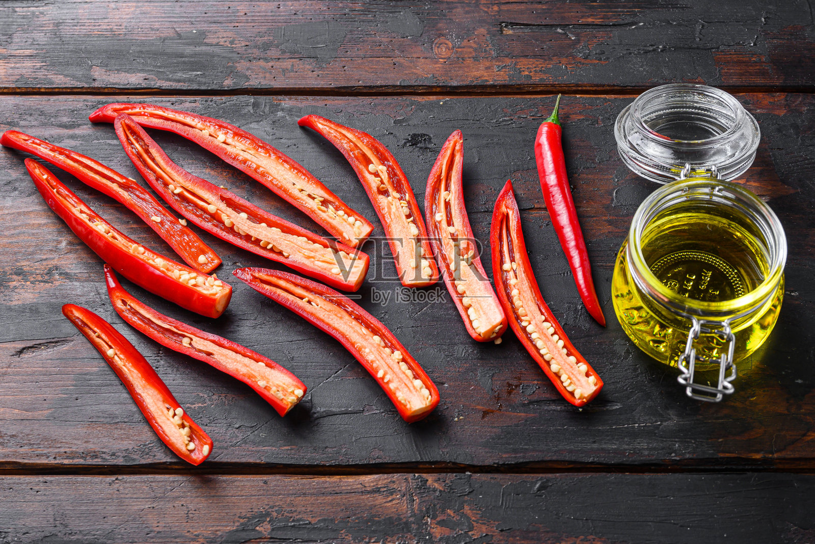 红辣椒切片制作辛辣的橄榄油在旧的深色木制桌子侧面视图。照片摄影图片