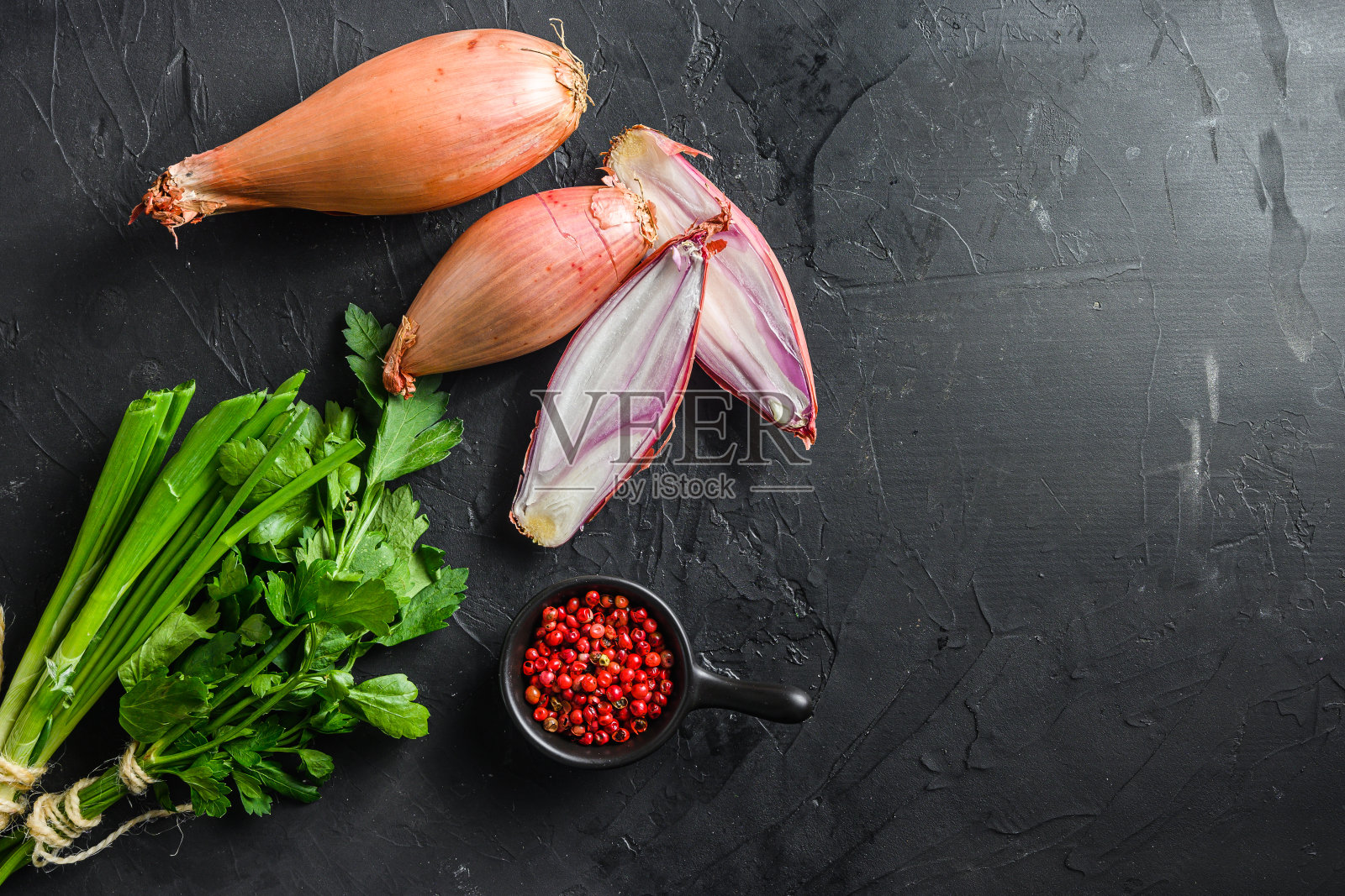 青葱,青葱或大葱生熟的洋葱与绿色和玫瑰花椒切成薄片和减半黑色混凝土纹理背景俯视图空间的文本照片摄影图片