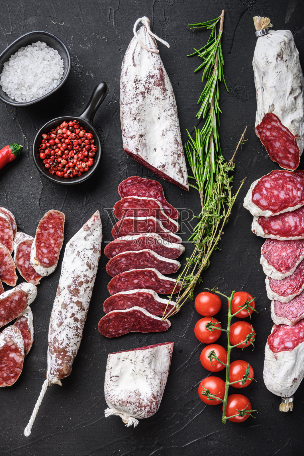 各种西班牙干腌腊肠片和整个切在黑色背景,俯视图照片摄影图片