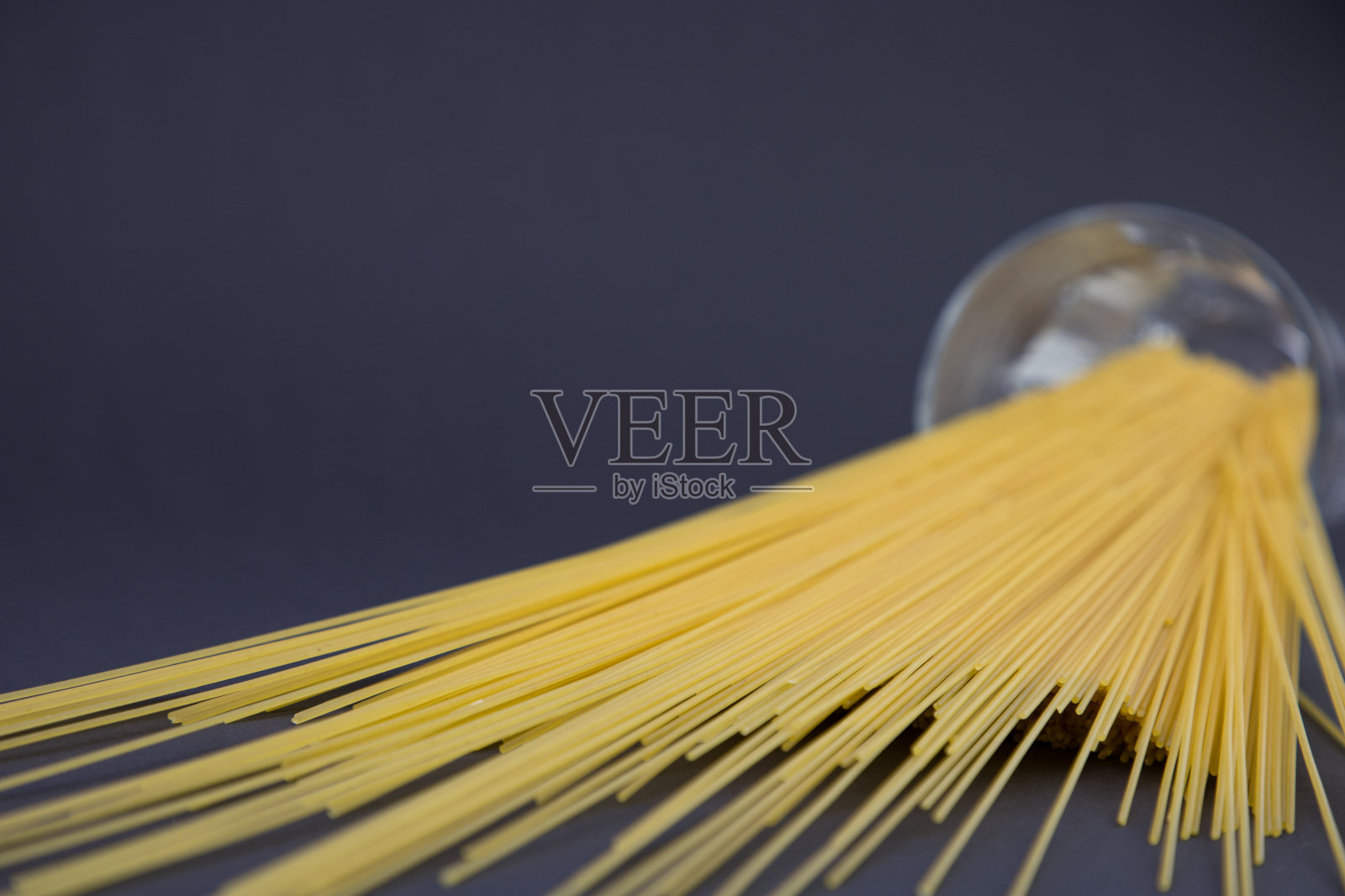 深色的背景上放着一个大杯子里的长通心粉照片摄影图片