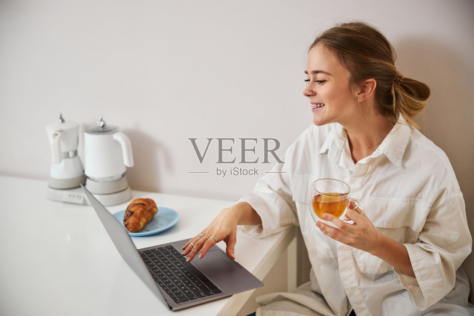 迷人的年轻女子喝茶和使用笔记本电脑照片摄影图片