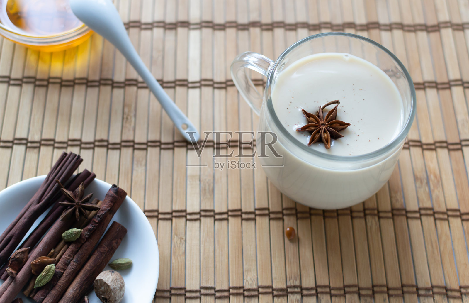 马萨拉茶在一个玻璃杯里,香料,蜂蜜和八角在一个木制的背景。照片摄影图片