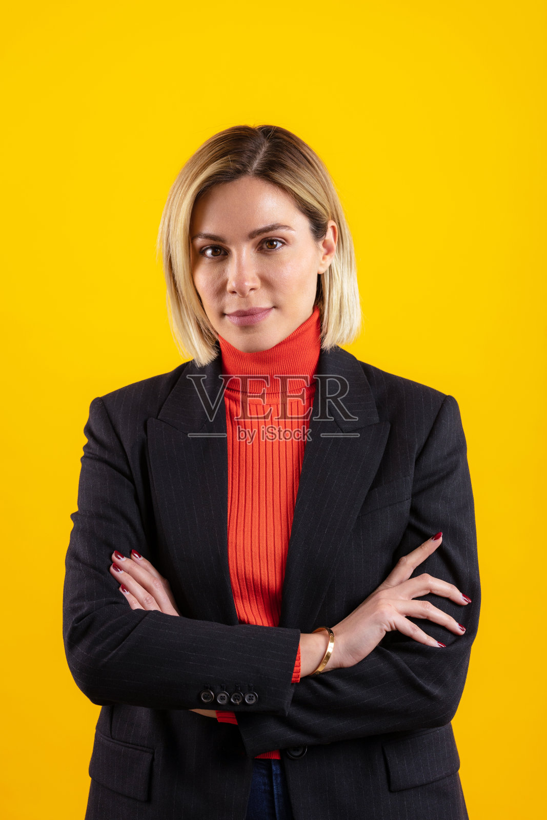 自信的女商人双臂交叉站在黄色背景下的肖像照片摄影图片