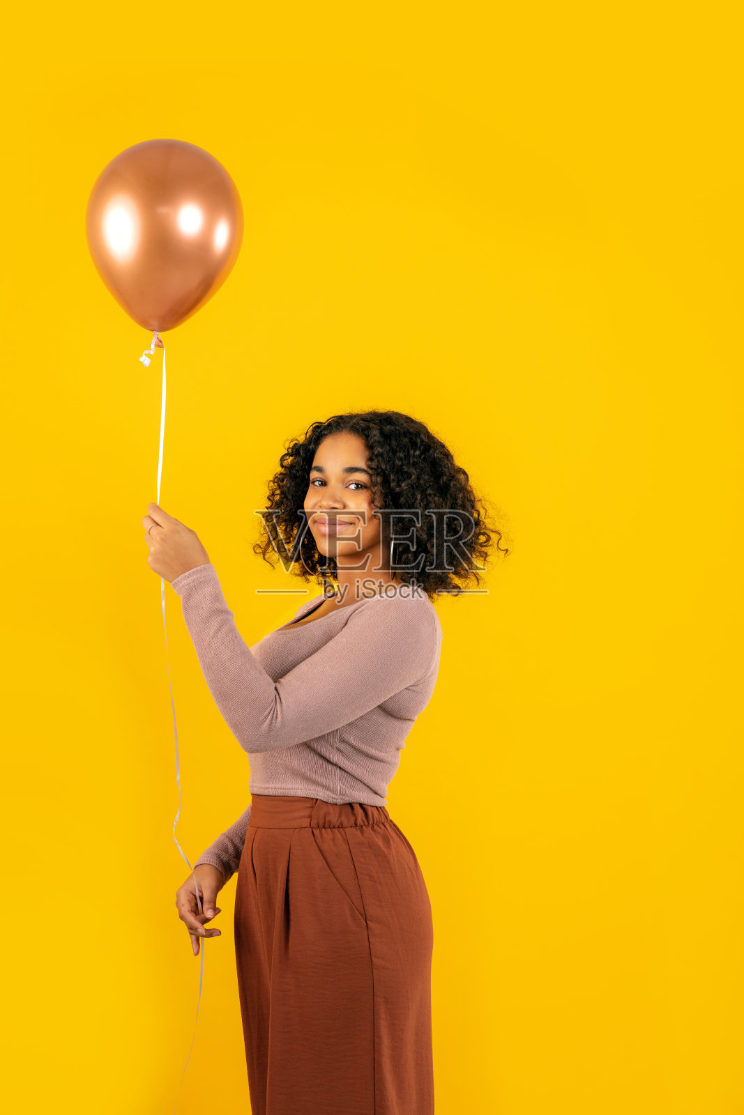 微笑的年轻女子拿着气球在黄色的背景照片摄影图片