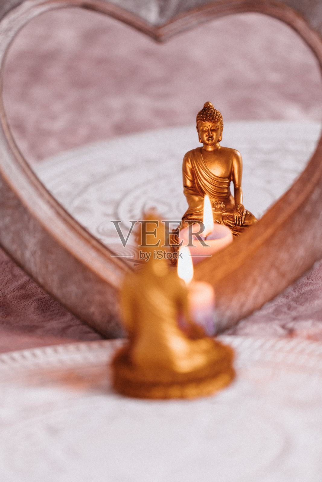 一个金色的佛像与蜡烛反映在心形镜子的特写照片摄影图片