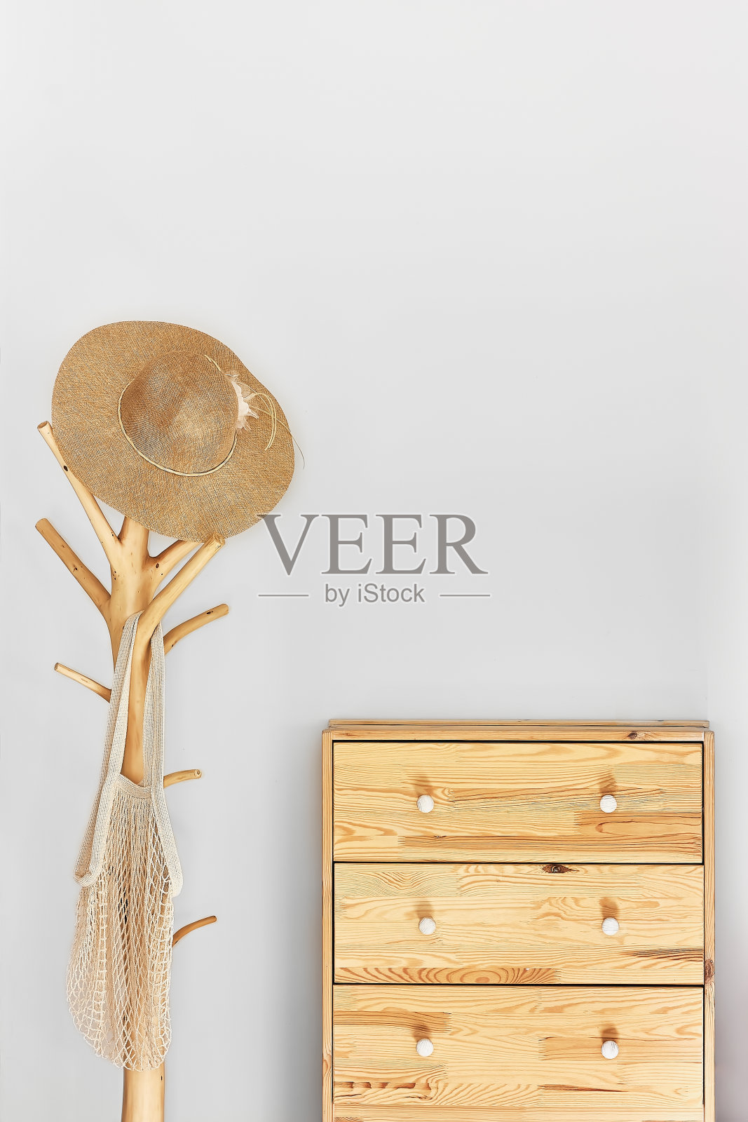 简约的走廊内饰,时髦的木制衣架架和背对灰色墙壁的马桶。衣架上有柳条帽和网眼袋。本空间照片摄影图片