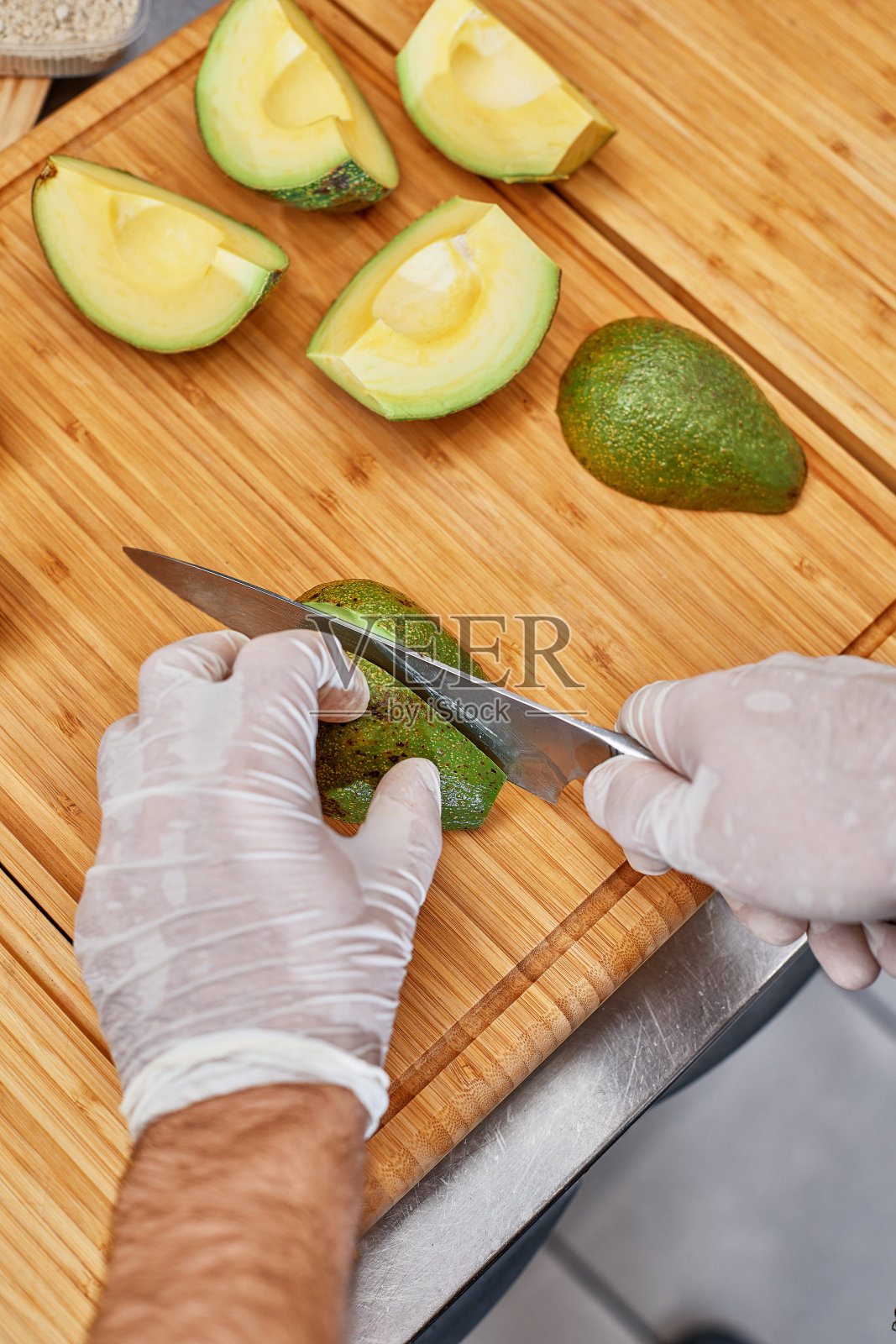 专业厨师在厨房桌子上切牛油果,特写照片摄影图片