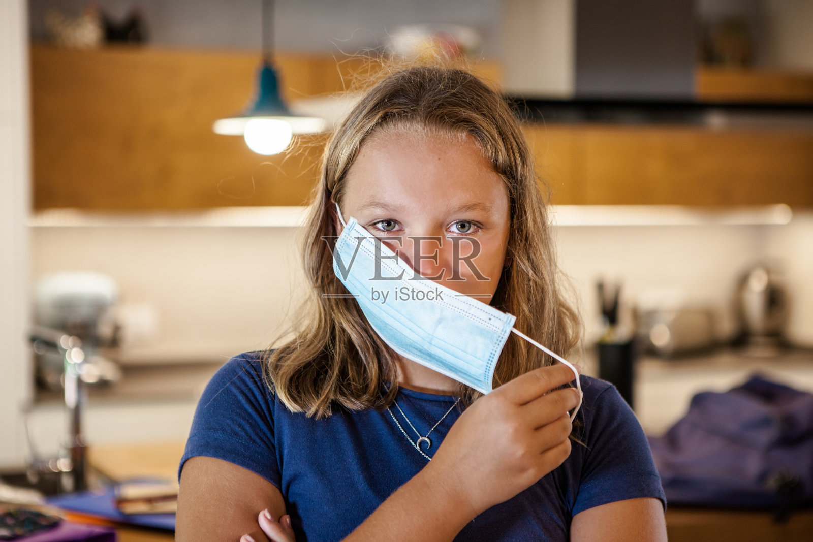 十几岁的女孩在上学前在家戴上防护面具。照片摄影图片