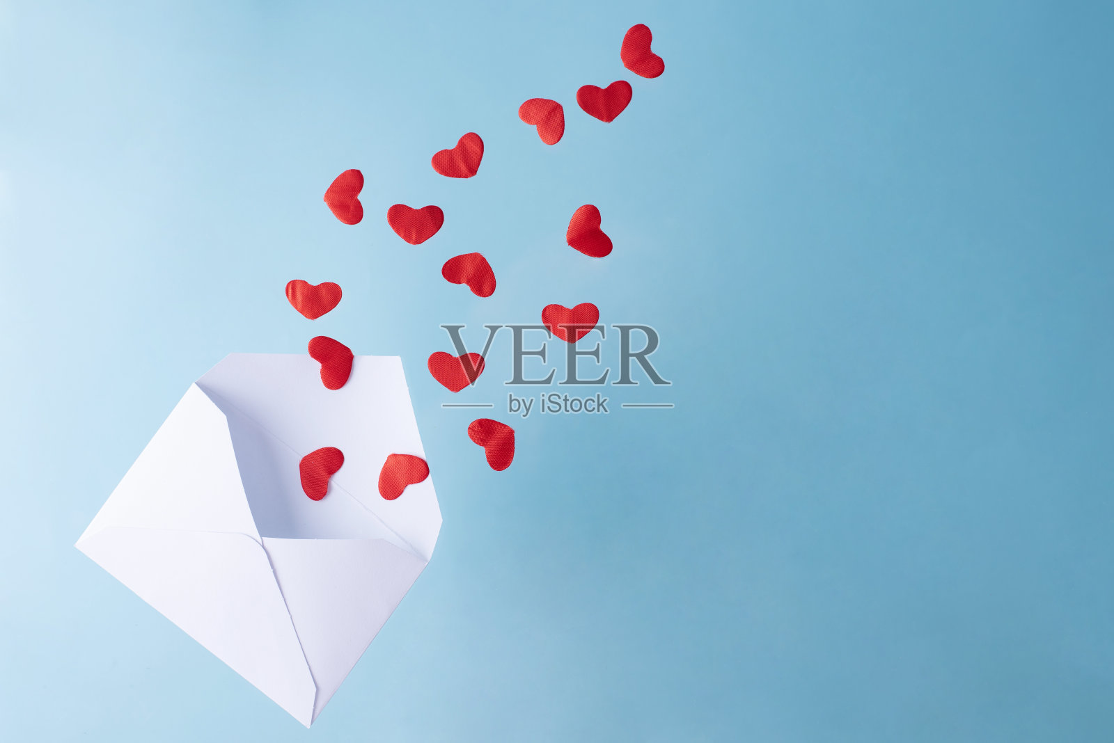 蓝底白信封里飞出红心。照片摄影图片