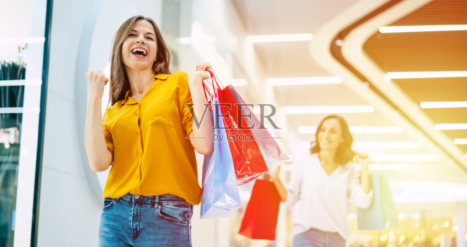 美丽、快乐、兴奋的年轻女孩朋友们拿着纸袋在商场里走来走去照片摄影图片